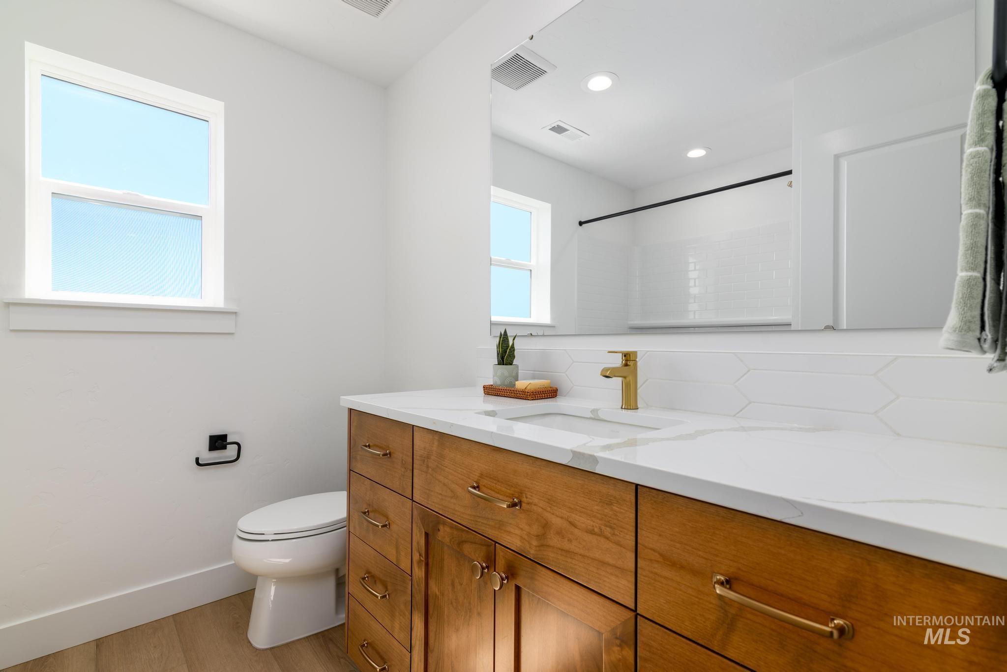 Full bathroom featuring vanity, wood finished floors, a shower, and recessed lighting