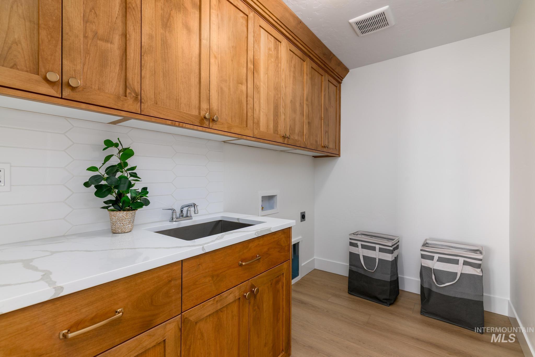 Laundry room featuring hookup for a washing machine, electric dryer hookup, light wood-style floors, and cabinet space