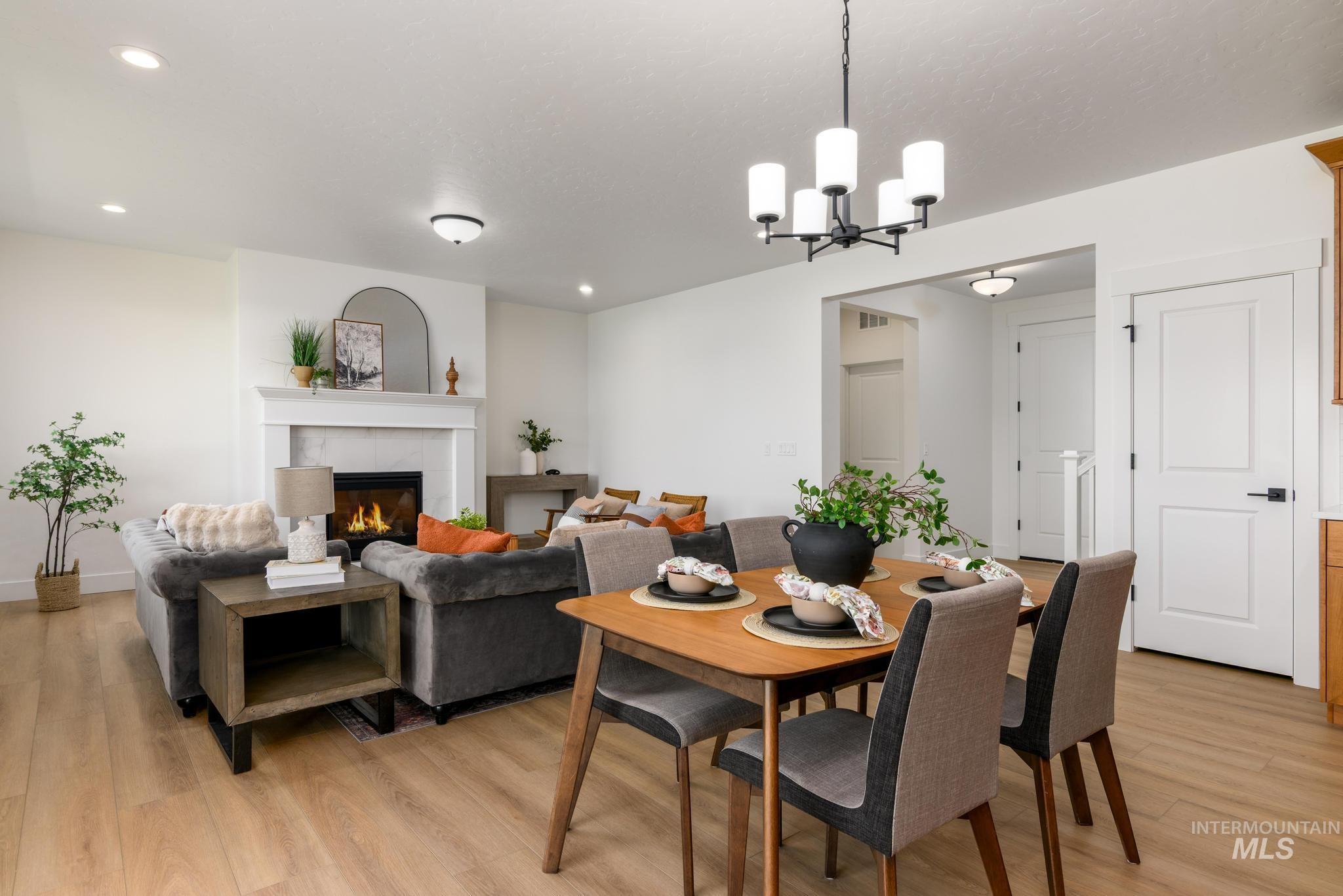 Dining area featuring a fireplace, light wood finished floors, recessed lighting, and a chandelier
