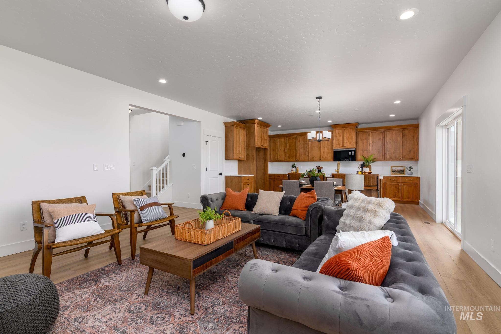 Living room with light wood-style flooring, recessed lighting, a chandelier, and stairs