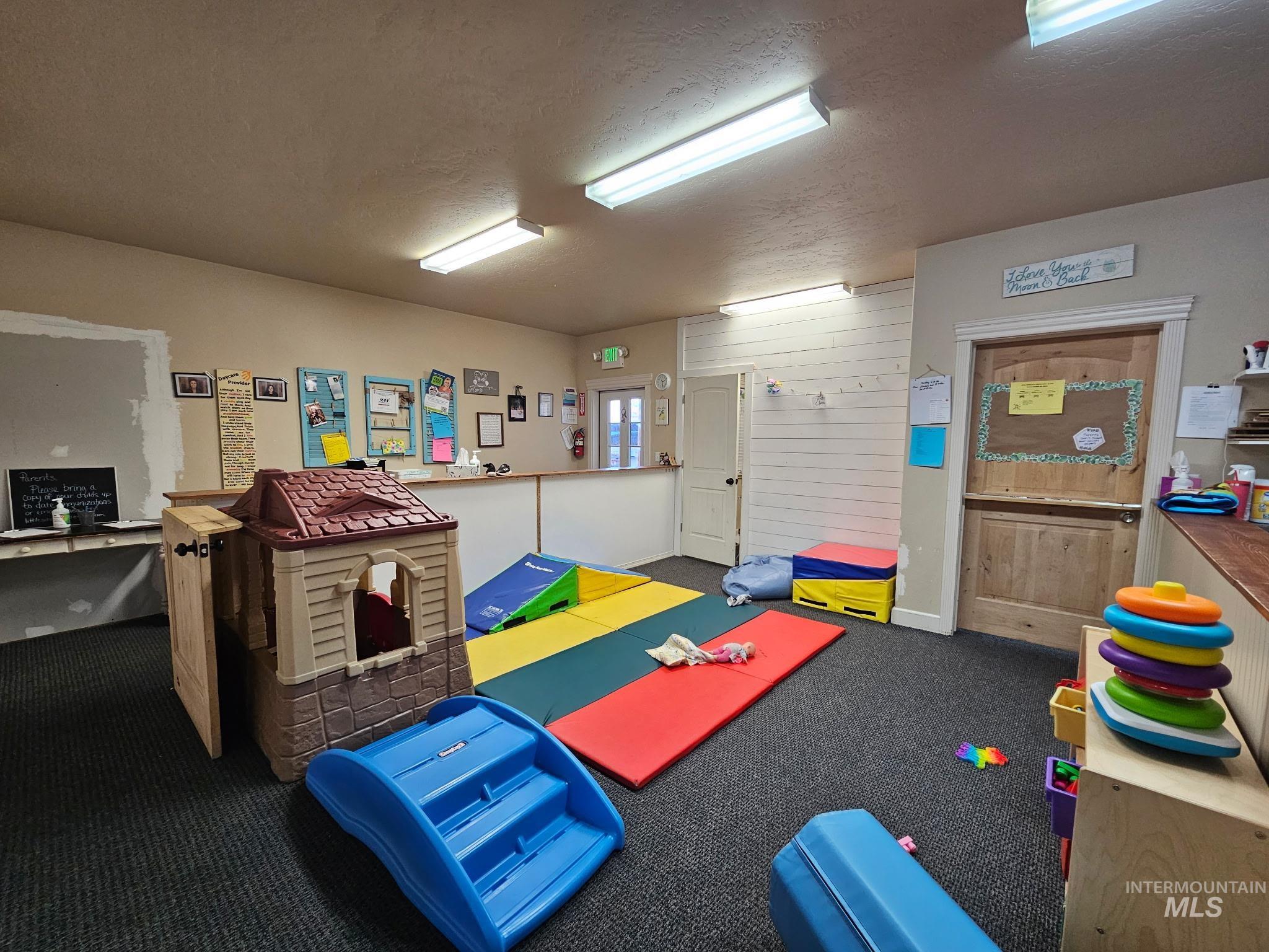 Playroom featuring a textured ceiling and carpet flooring