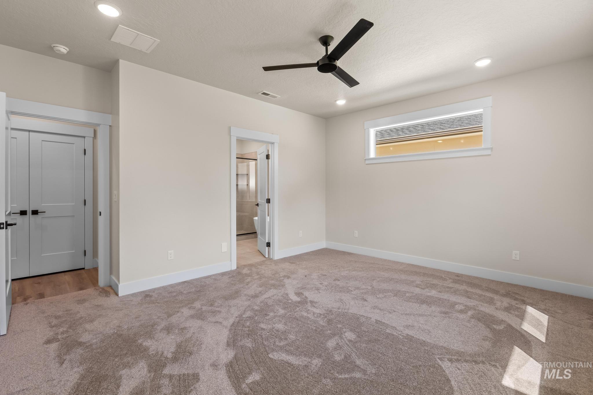 Unfurnished bedroom featuring light colored carpet, a ceiling fan, recessed lighting, and ensuite bathroom