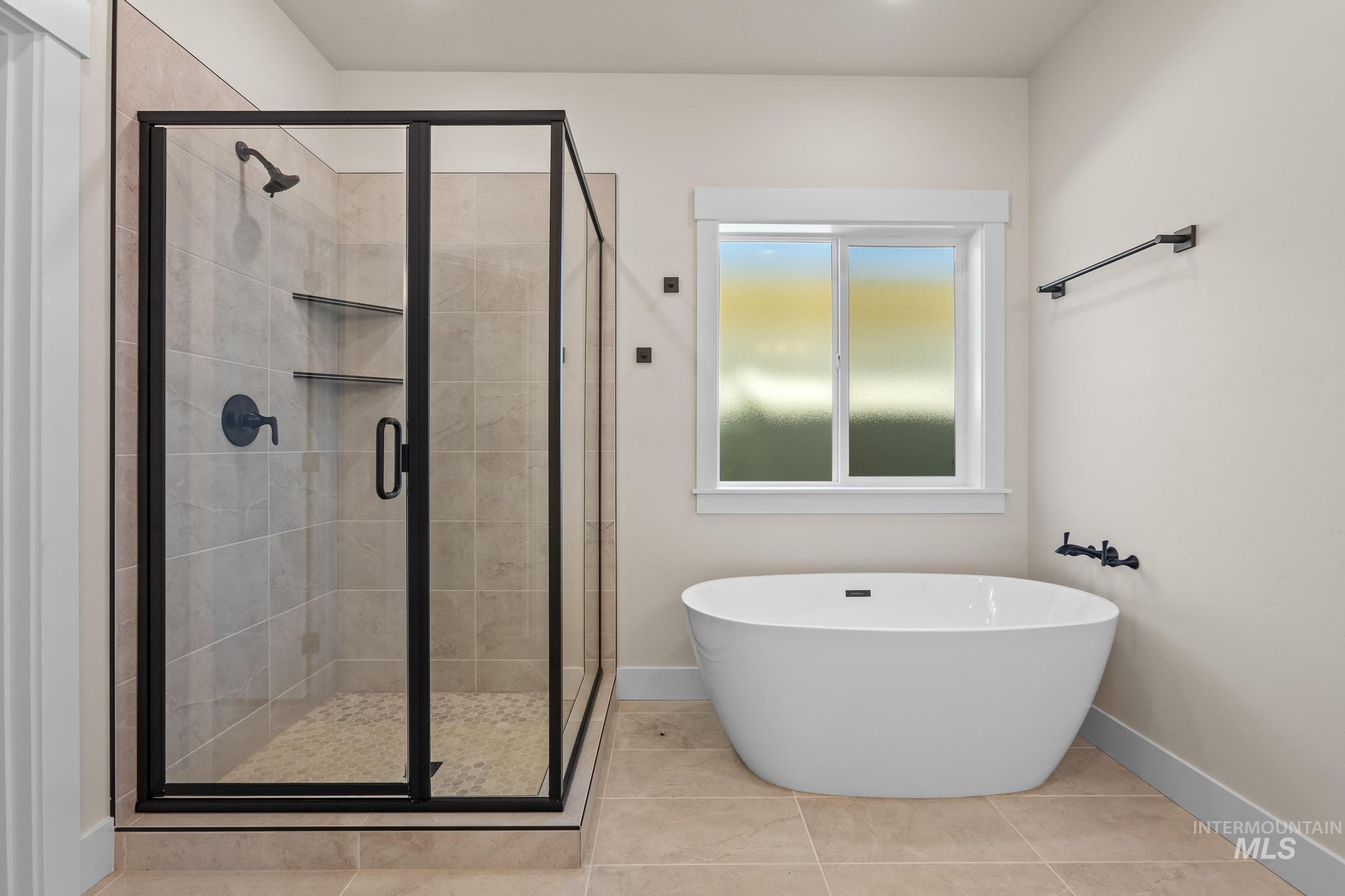 Bathroom featuring a shower stall, a freestanding bath, and tile patterned floors