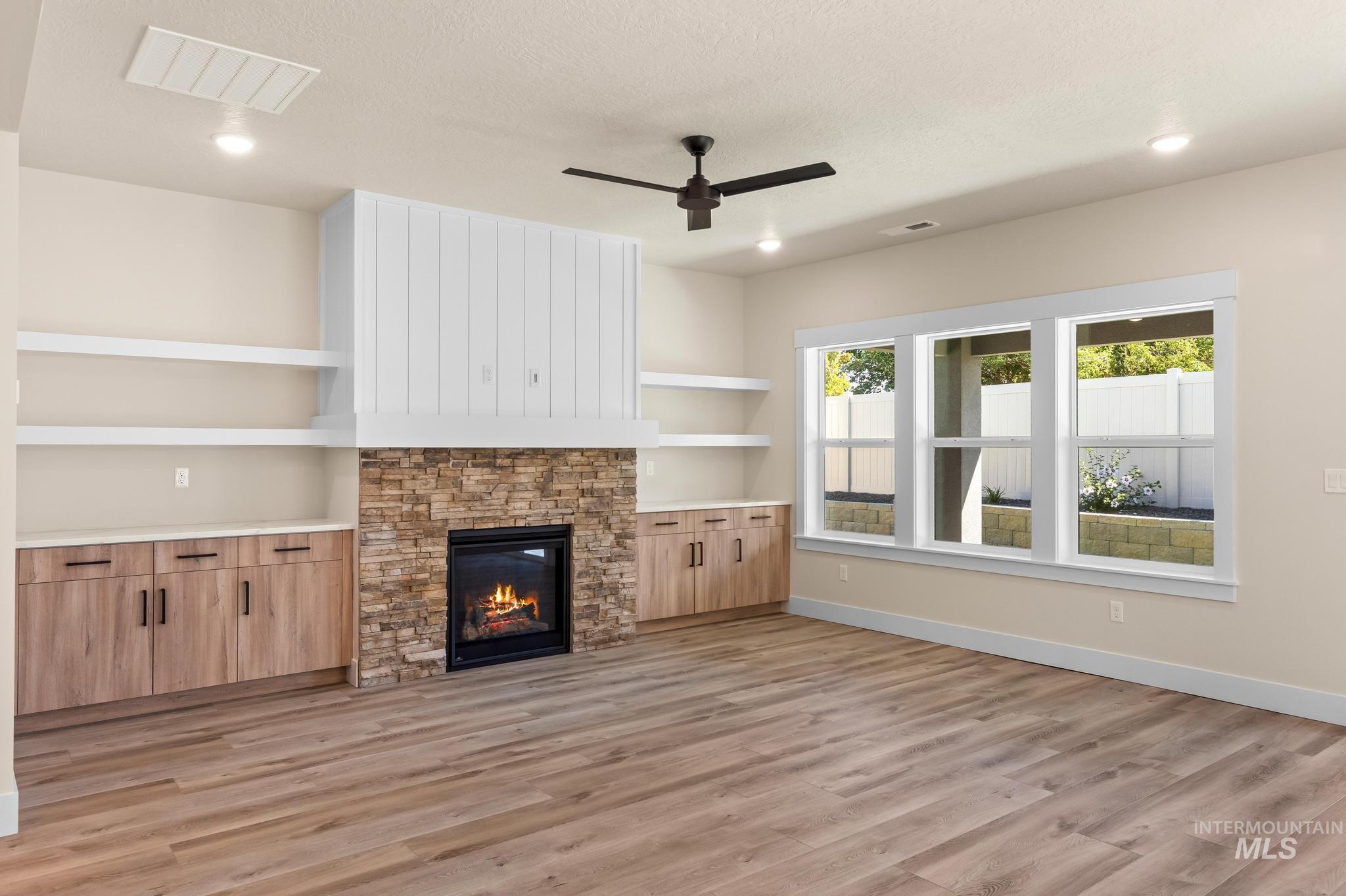 Unfurnished living room featuring a fireplace, light wood-style flooring, a ceiling fan, built in features, and recessed lighting