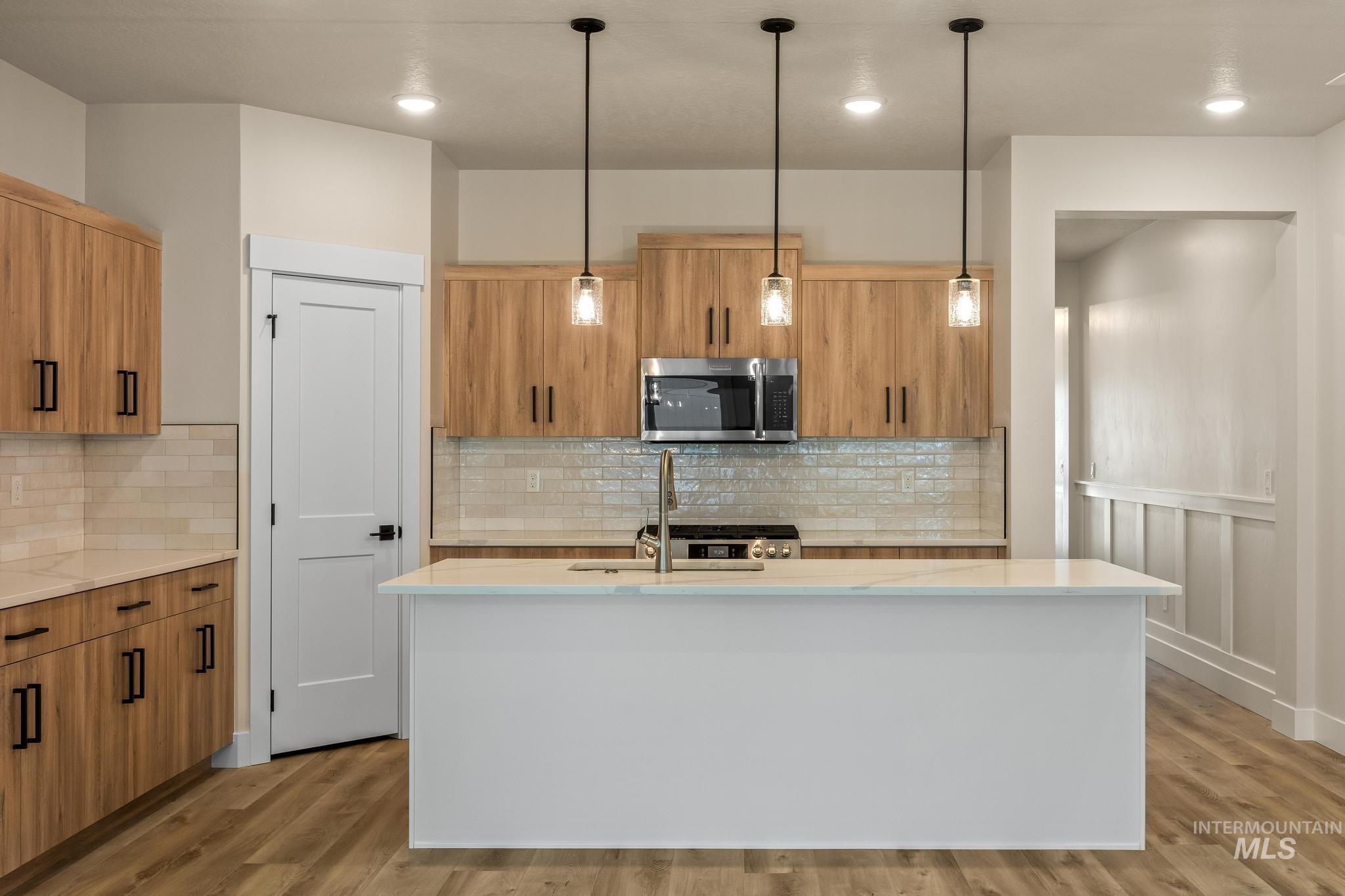Kitchen with light stone countertops, modern cabinets, pendant lighting, appliances with stainless steel finishes, and recessed lighting