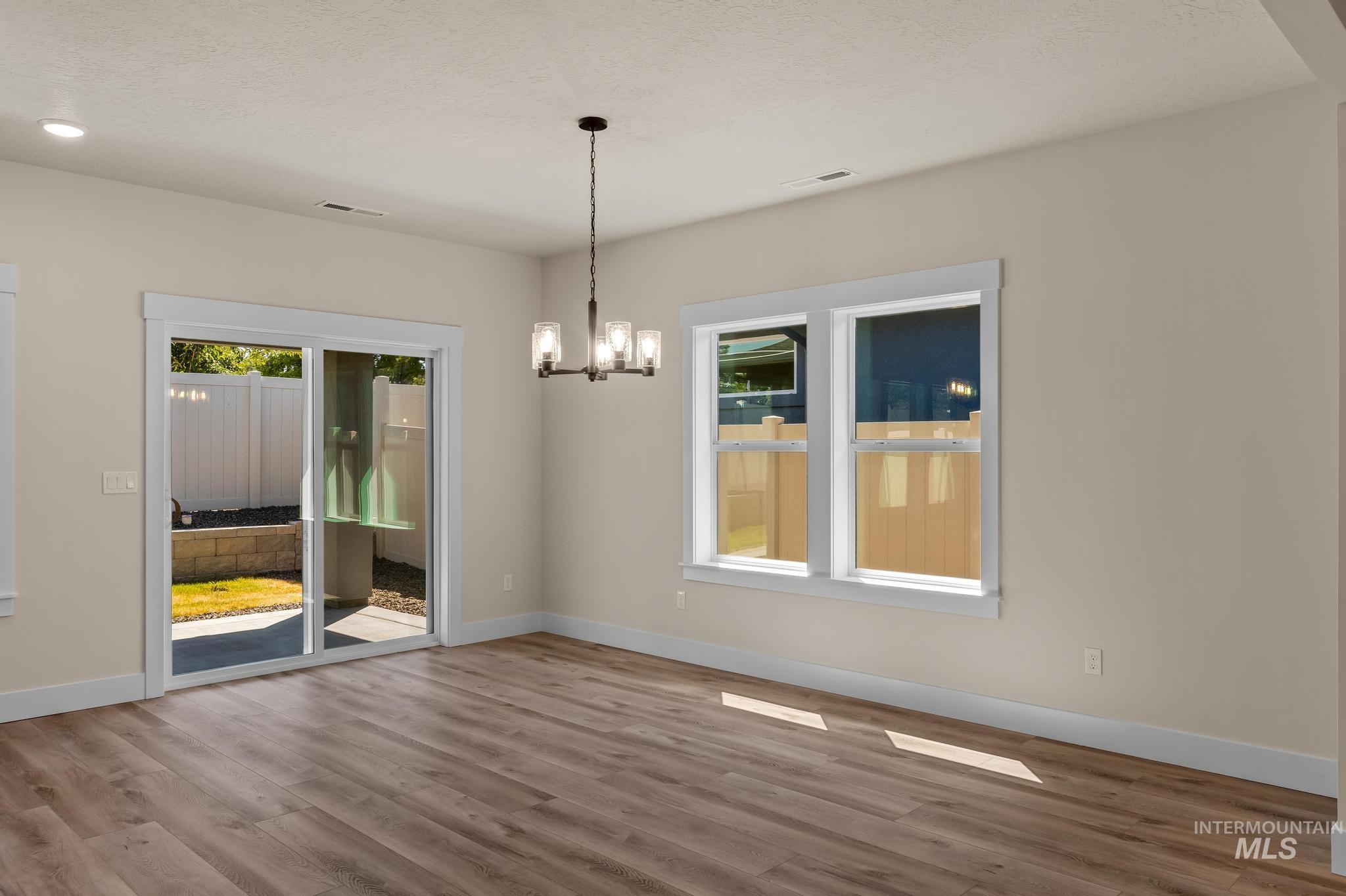 Unfurnished dining area featuring a chandelier and wood finished floors