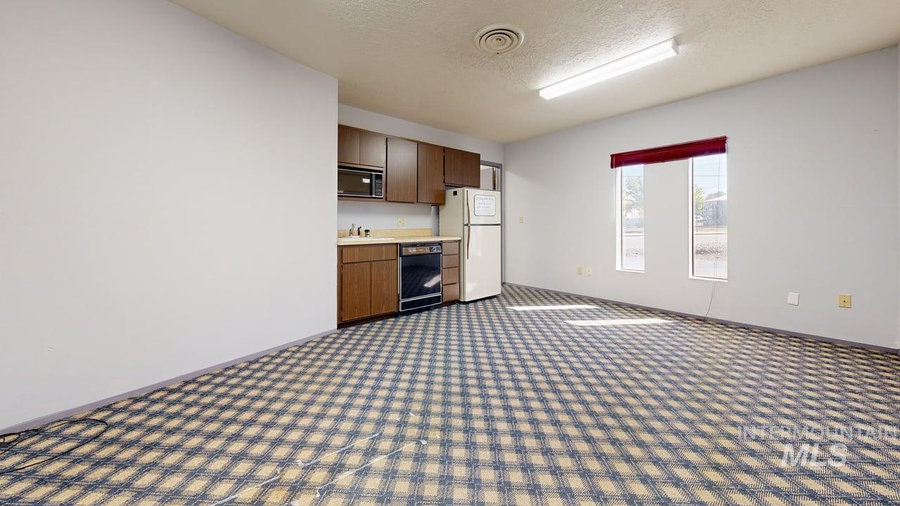 Kitchen featuring light countertops, a textured ceiling, black appliances, dark carpet, and dark brown cabinetry