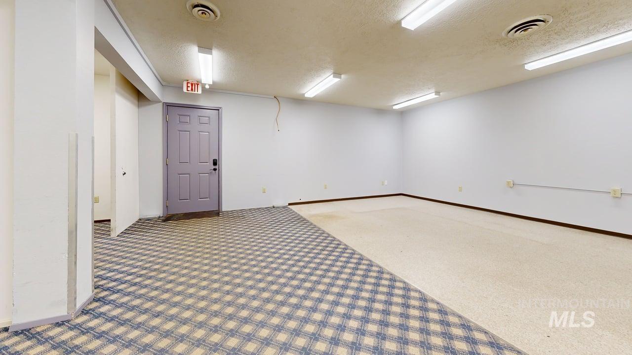 Carpeted spare room with a textured ceiling and baseboards