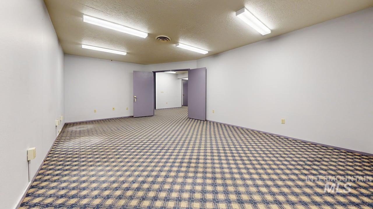 Carpeted spare room with a textured ceiling and baseboards