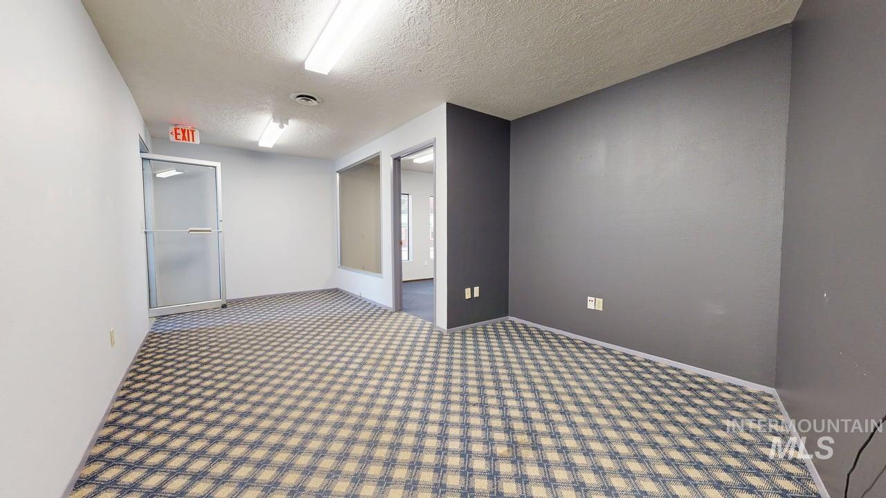 Carpeted spare room featuring a textured ceiling and baseboards
