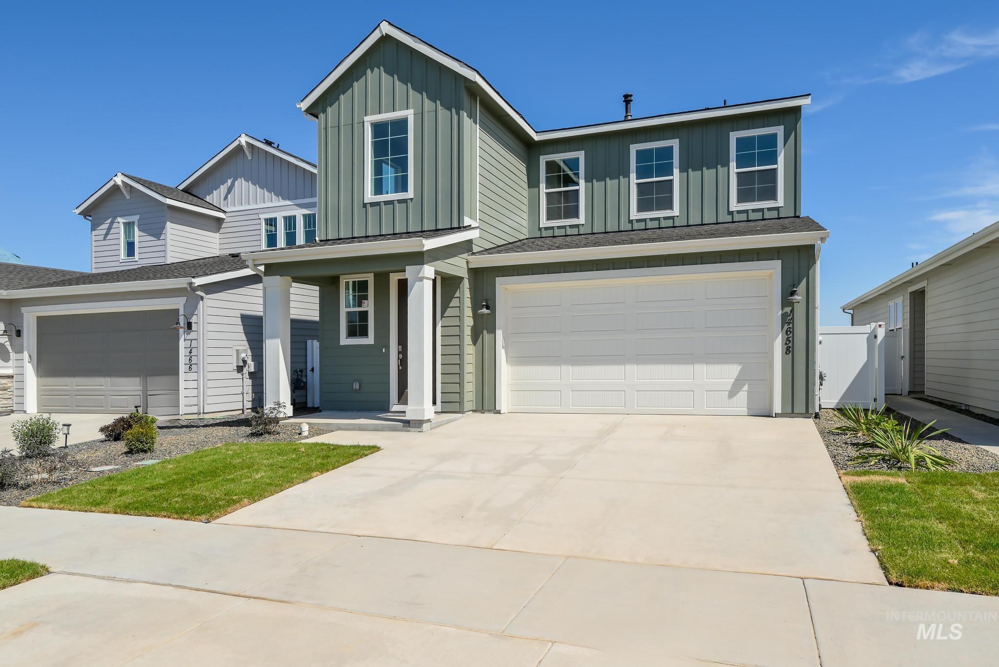 View of front facade featuring board and batten siding, driveway, a garage, and covered porch