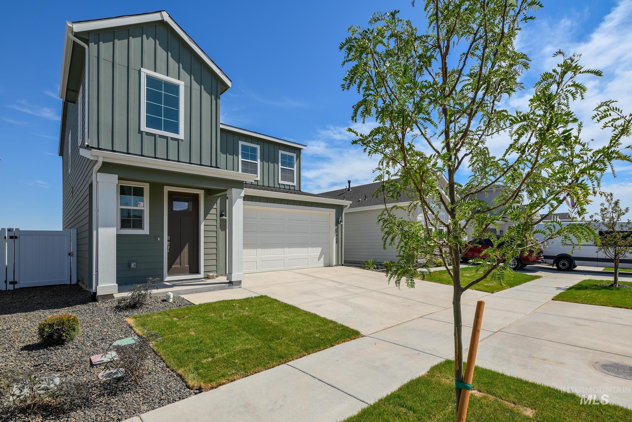 View of front of property featuring board and batten siding, concrete driveway, a gate, and an attached garage