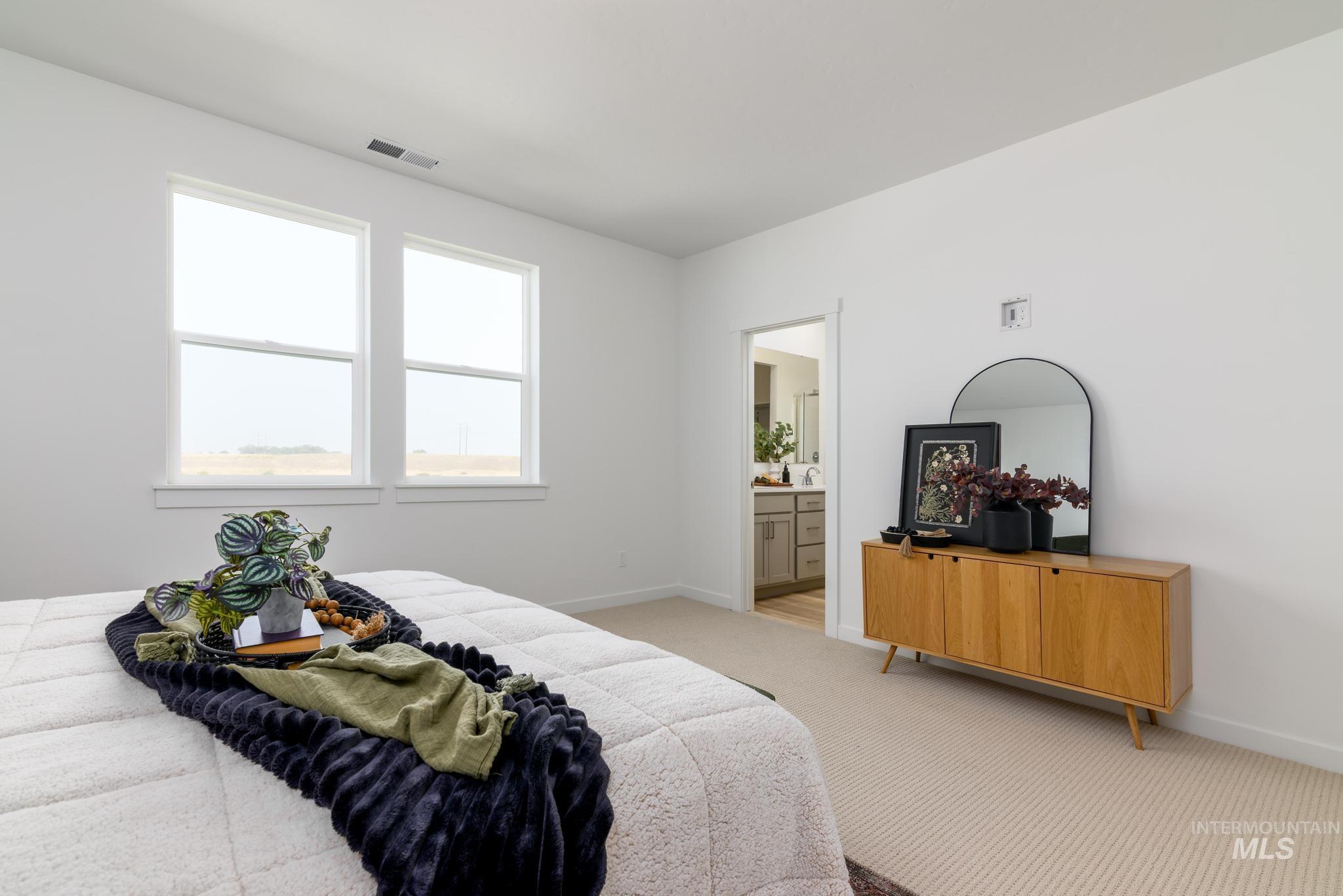 Carpeted bedroom featuring baseboards and connected bathroom