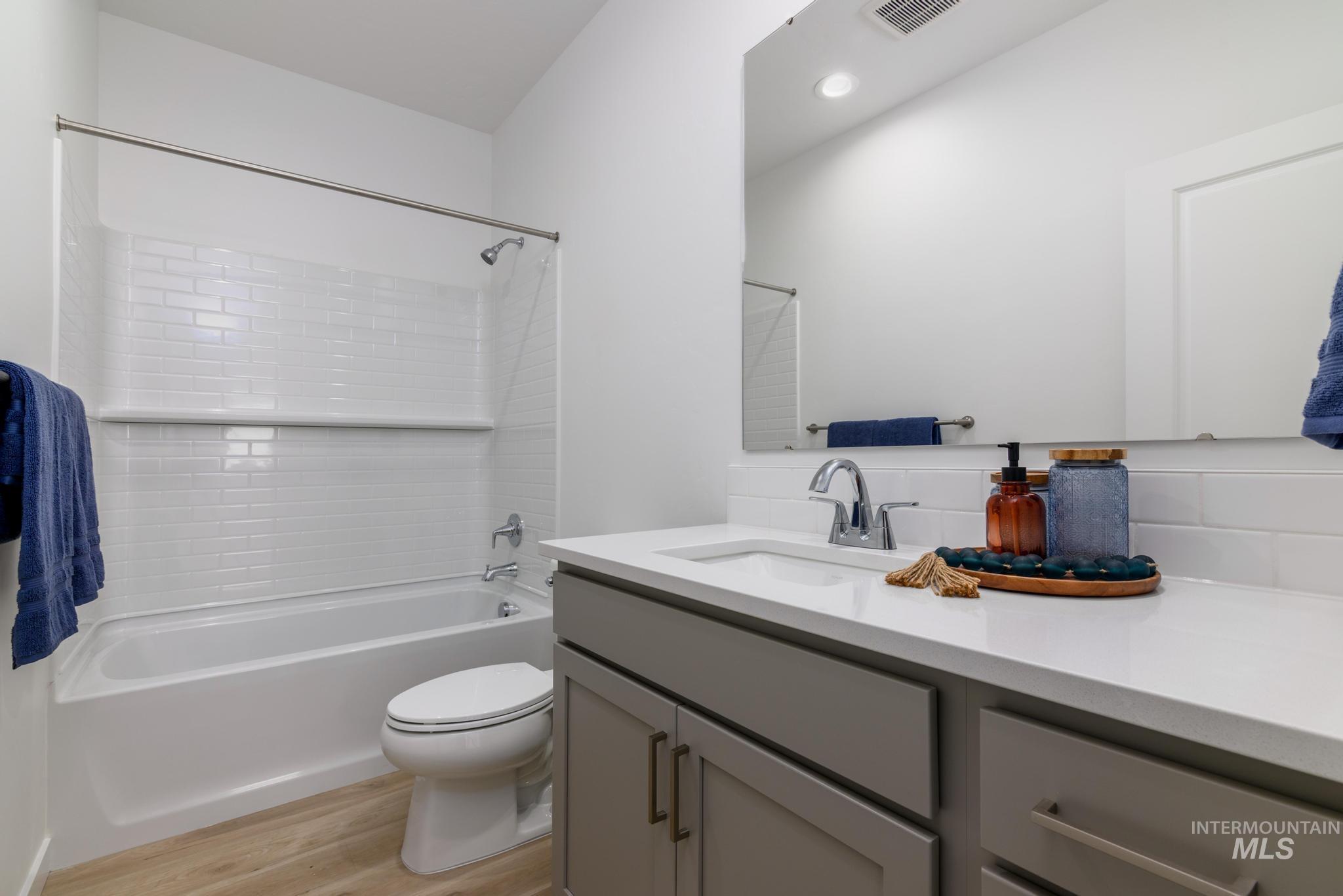 Full bath with shower / bathtub combination, light wood-style floors, and vanity