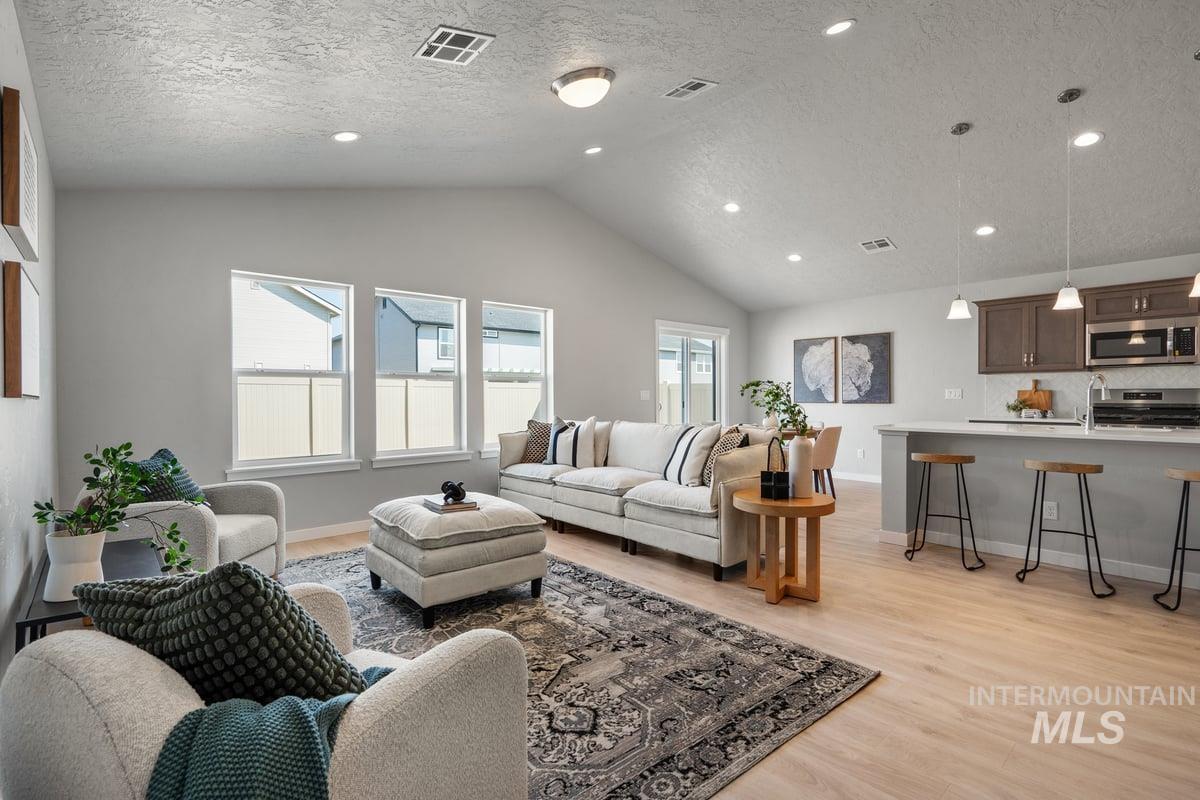 Living area featuring light wood finished floors, a textured ceiling, recessed lighting, and vaulted ceiling