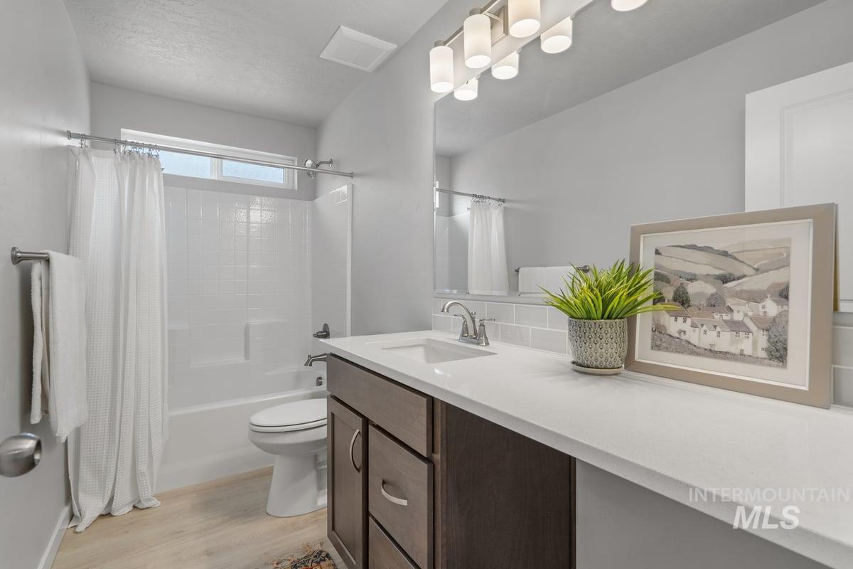 Bathroom featuring shower / bath combo, vanity, light wood-style flooring, and a textured ceiling