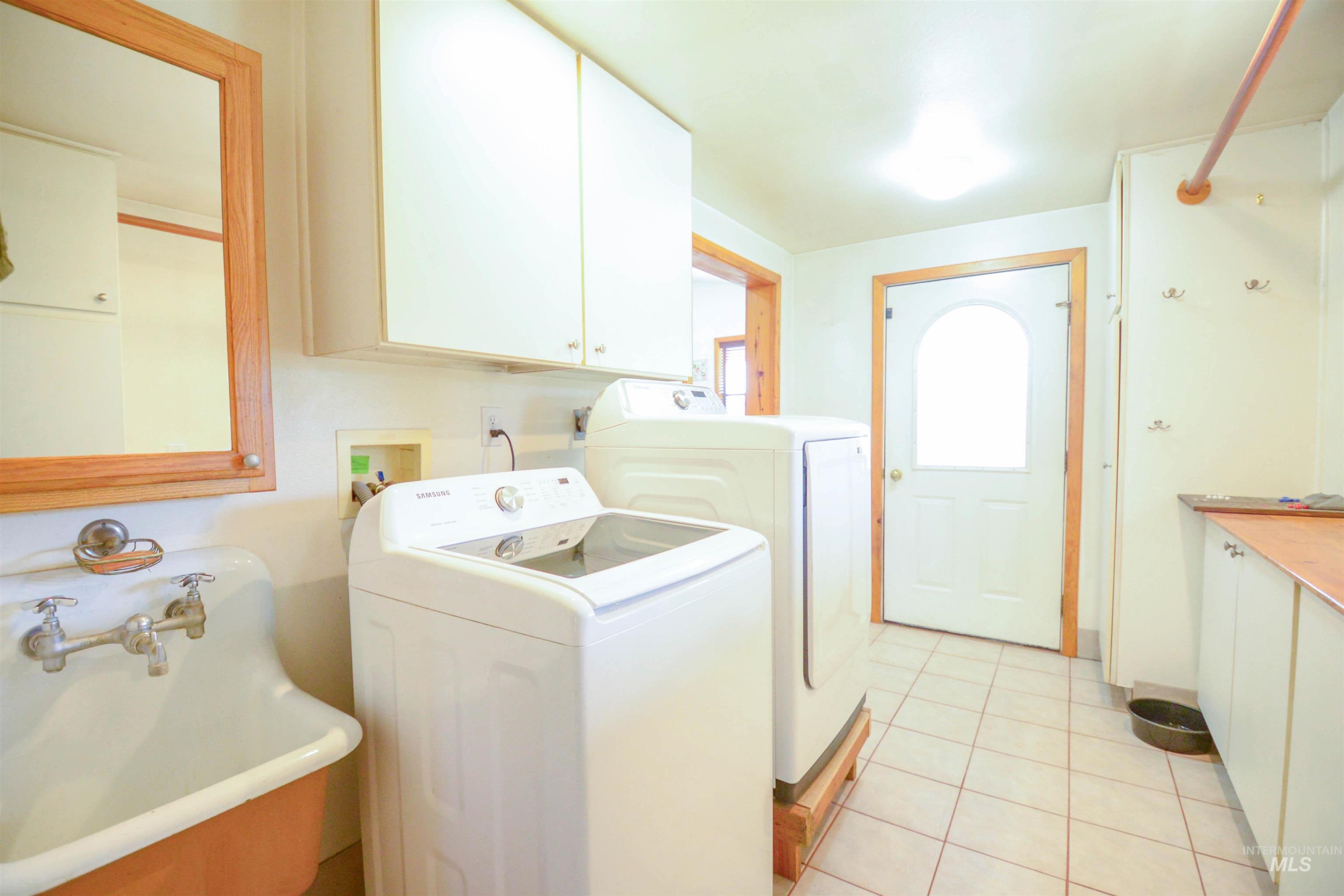 Washroom featuring washer and dryer, light tile patterned flooring, and cabinet space