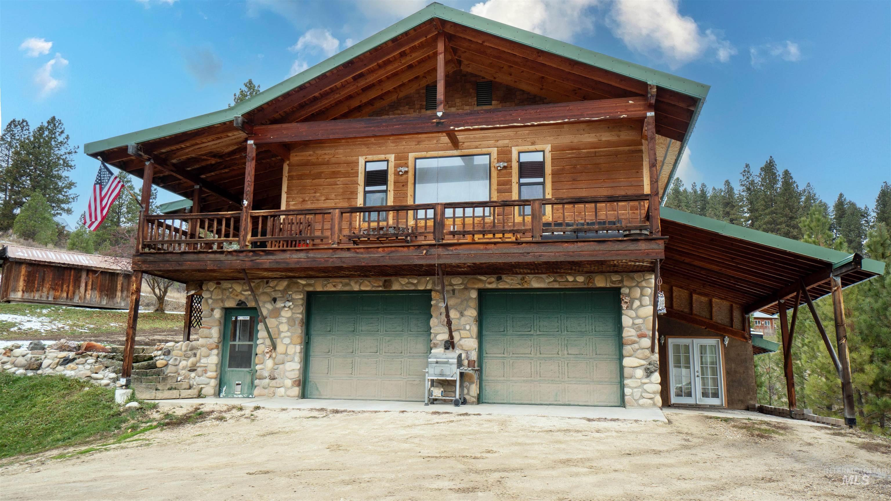 View of front of property featuring stone siding, driveway, french doors, and an attached garage