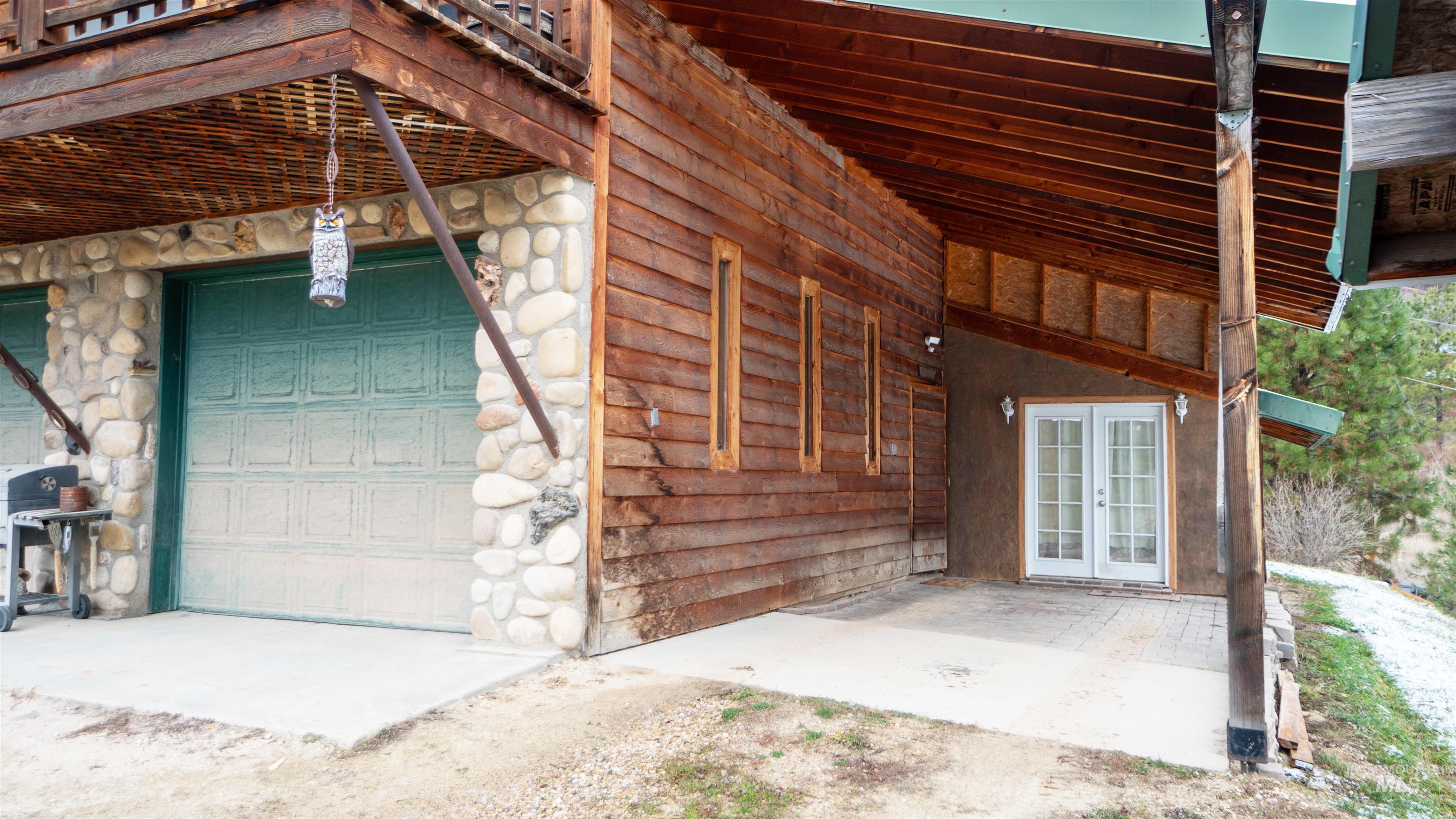 Entrance to property with a garage, stone siding, a patio, and french doors