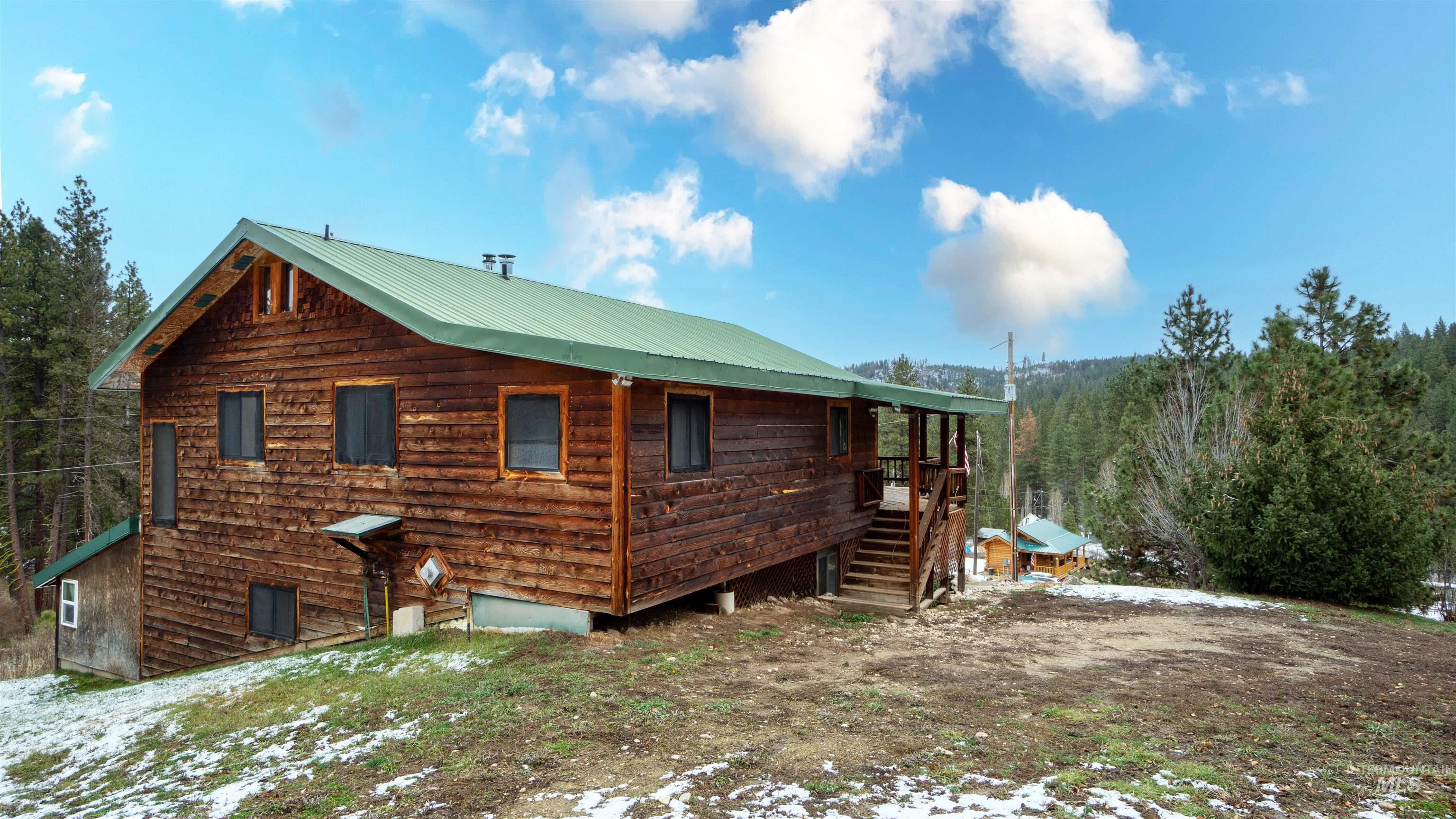 View of snow covered exterior with a metal roof and stairway