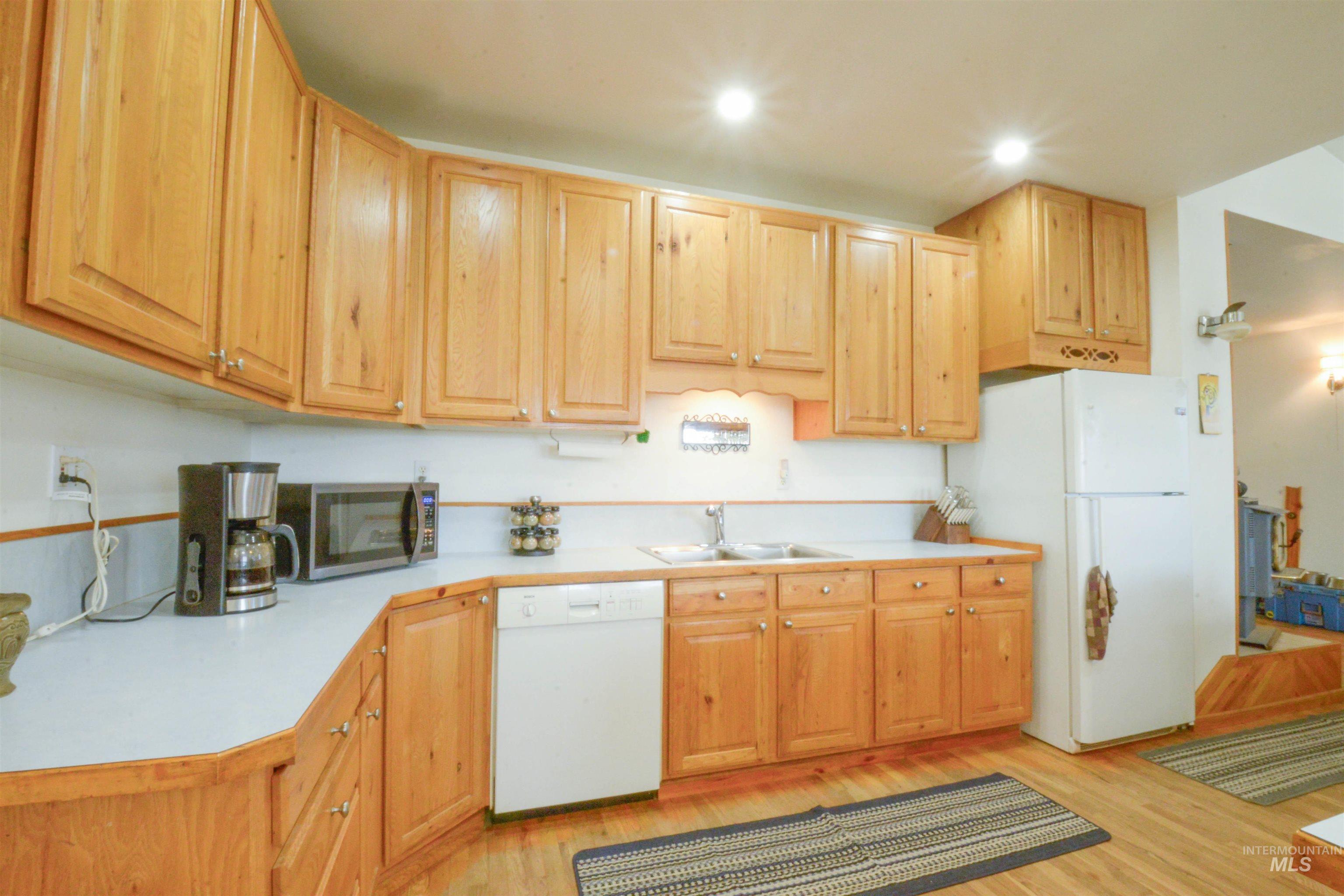 Kitchen featuring light countertops, white appliances, and light wood-type flooring