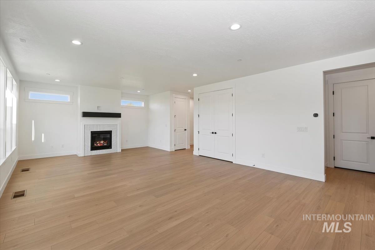 Unfurnished living room with light wood-type flooring, a tile fireplace, and recessed lighting