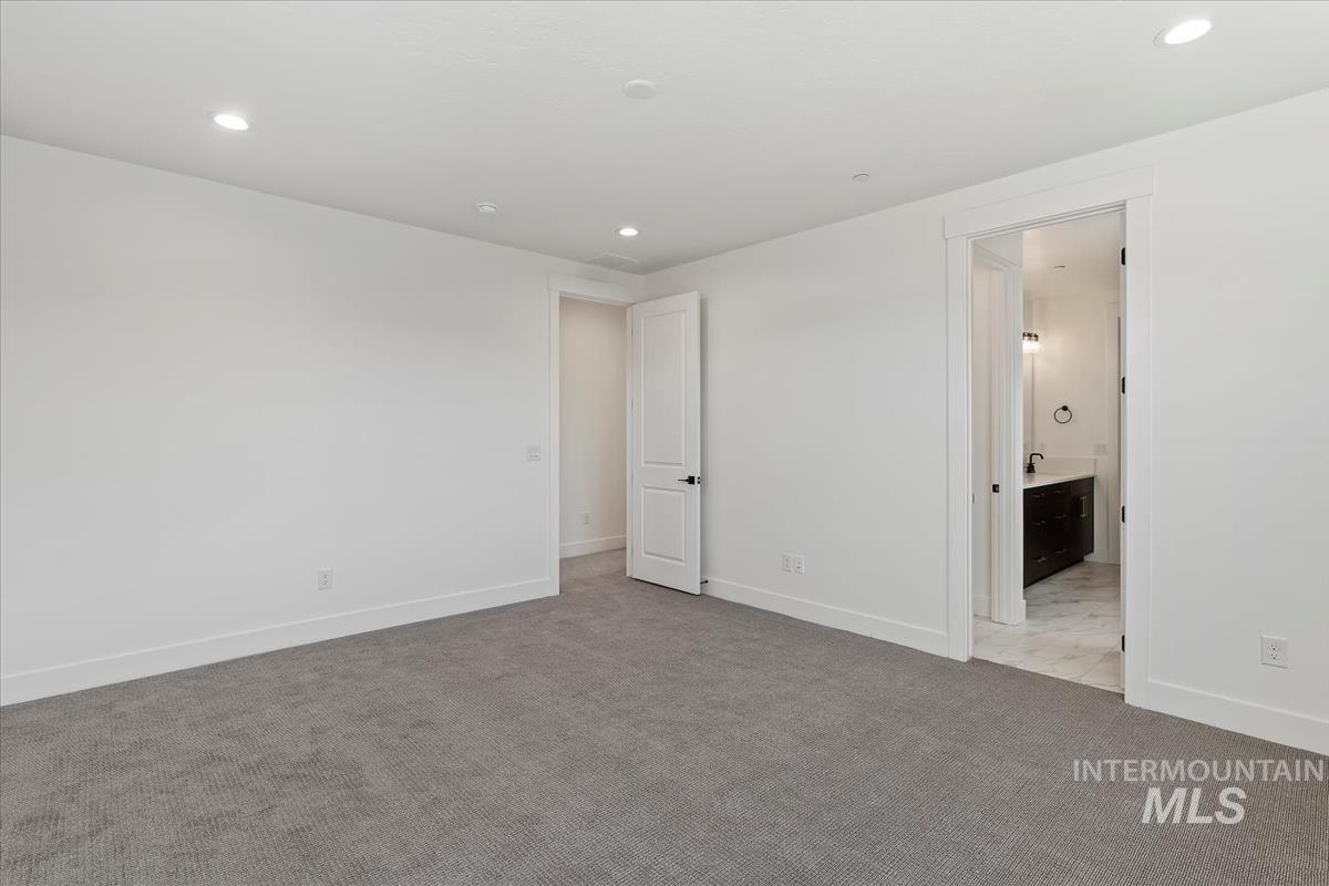 Unfurnished bedroom with light colored carpet, recessed lighting, and ensuite bath
