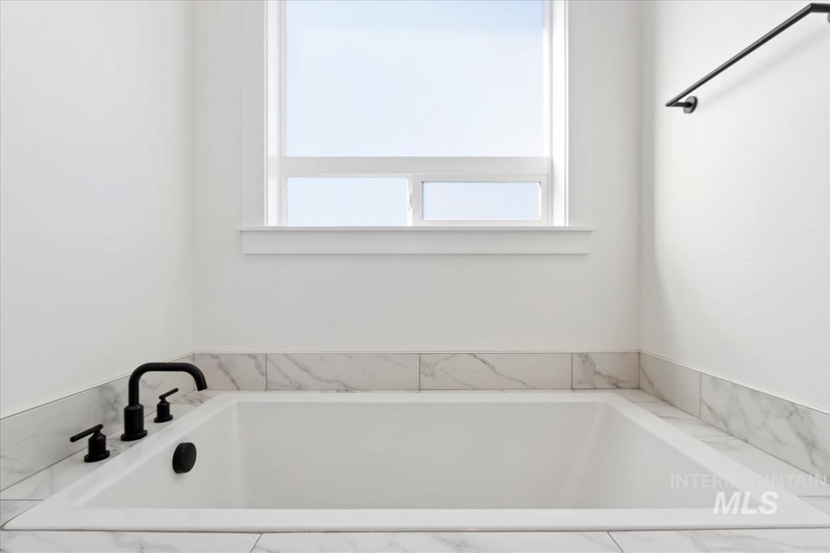 Bathroom featuring a tub with marble appearance