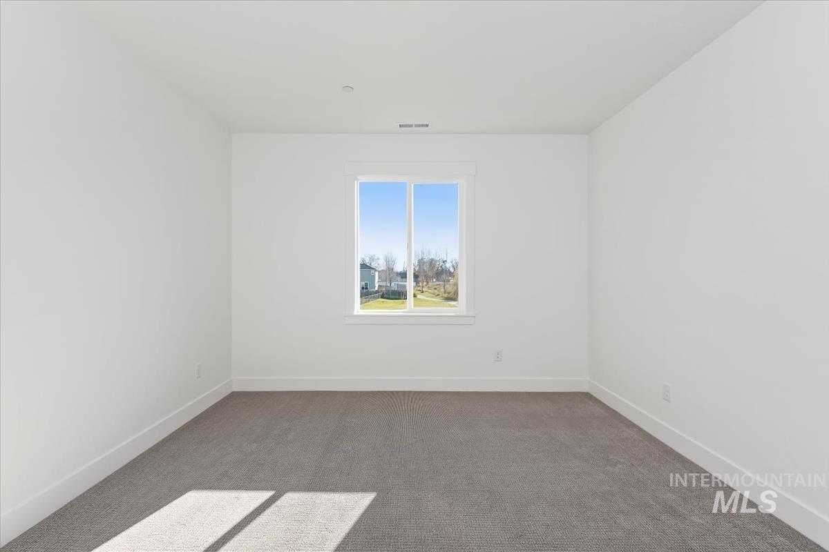 Carpeted spare room featuring baseboards