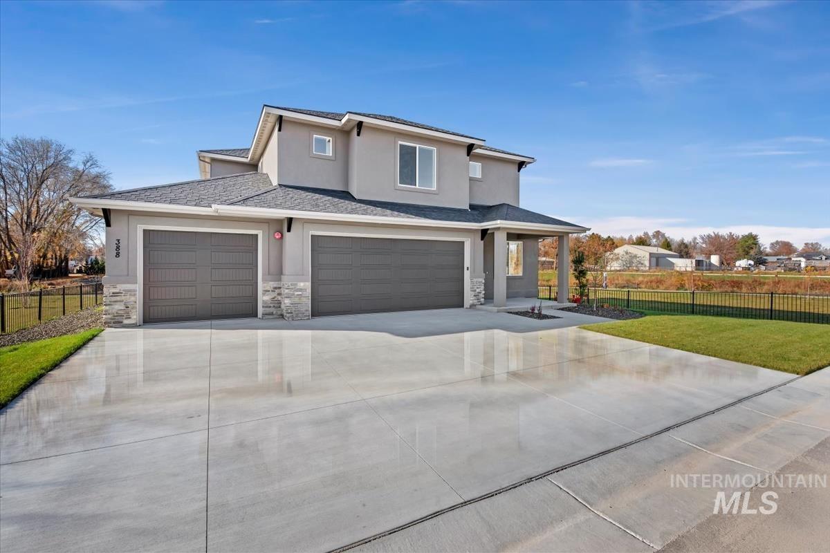 View of front of home with driveway, stucco siding, stone siding, an attached garage, and roof with shingles