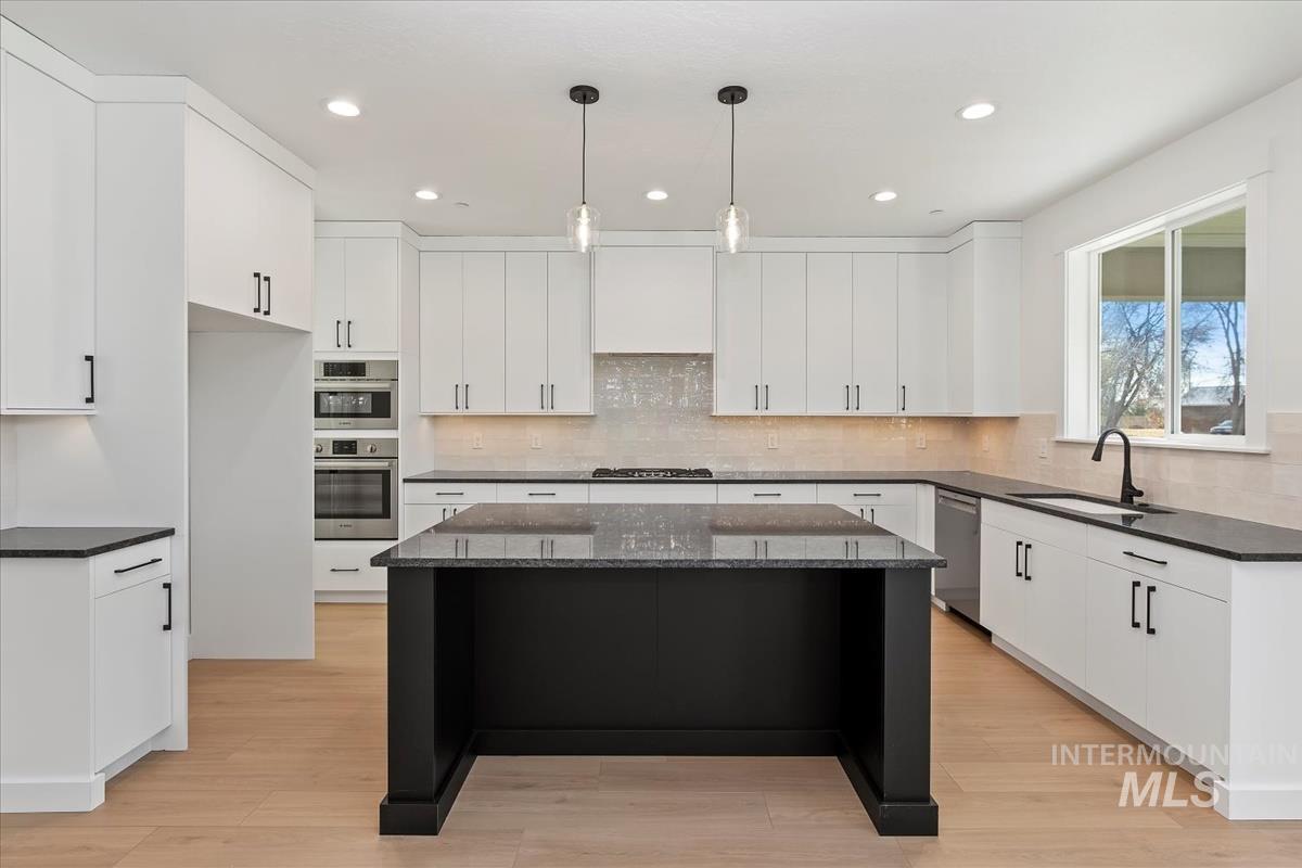Kitchen featuring dark stone counters, pendant lighting, white cabinets, recessed lighting, and light wood-type flooring