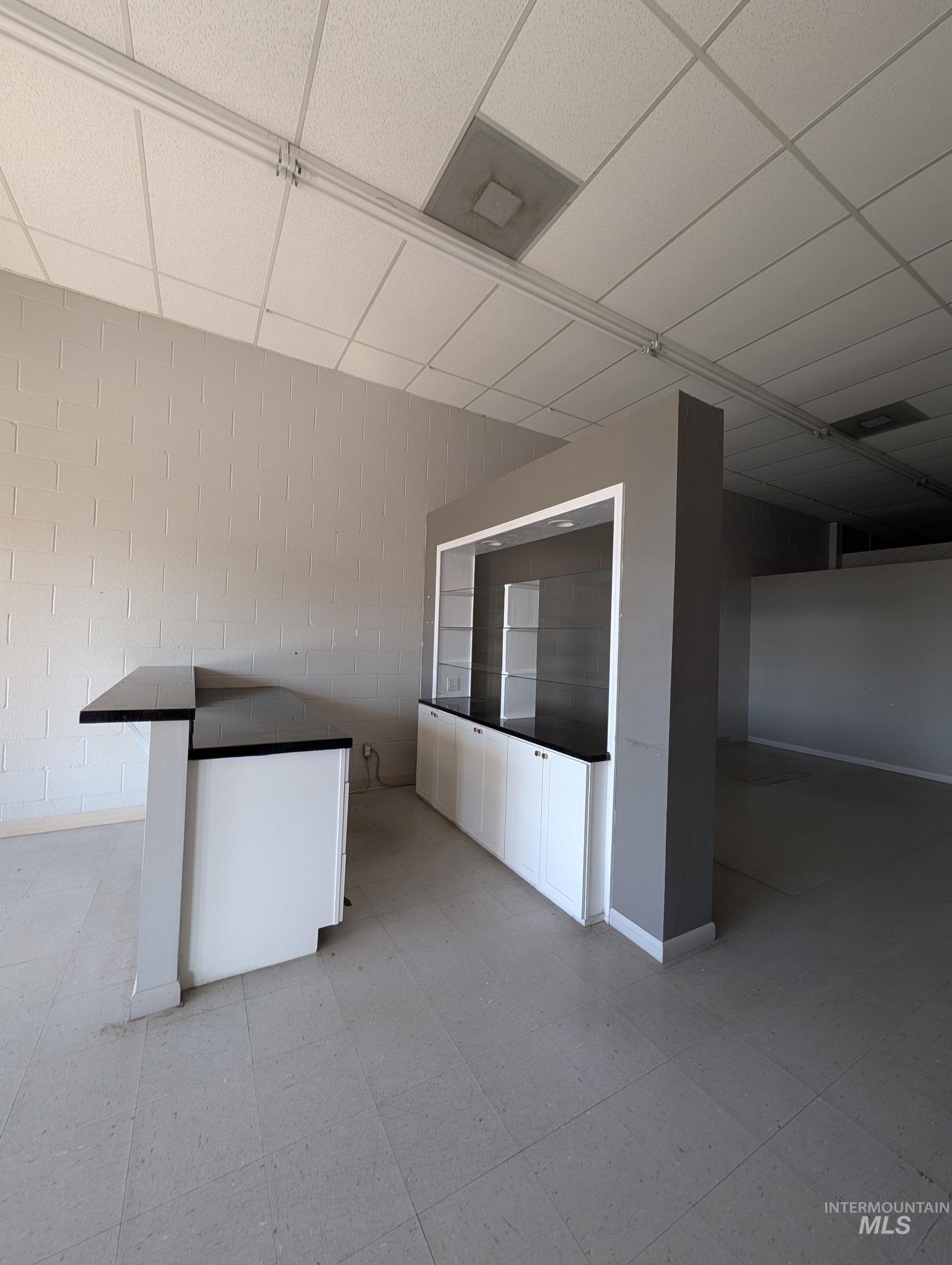 Interior space featuring a paneled ceiling and concrete block wall