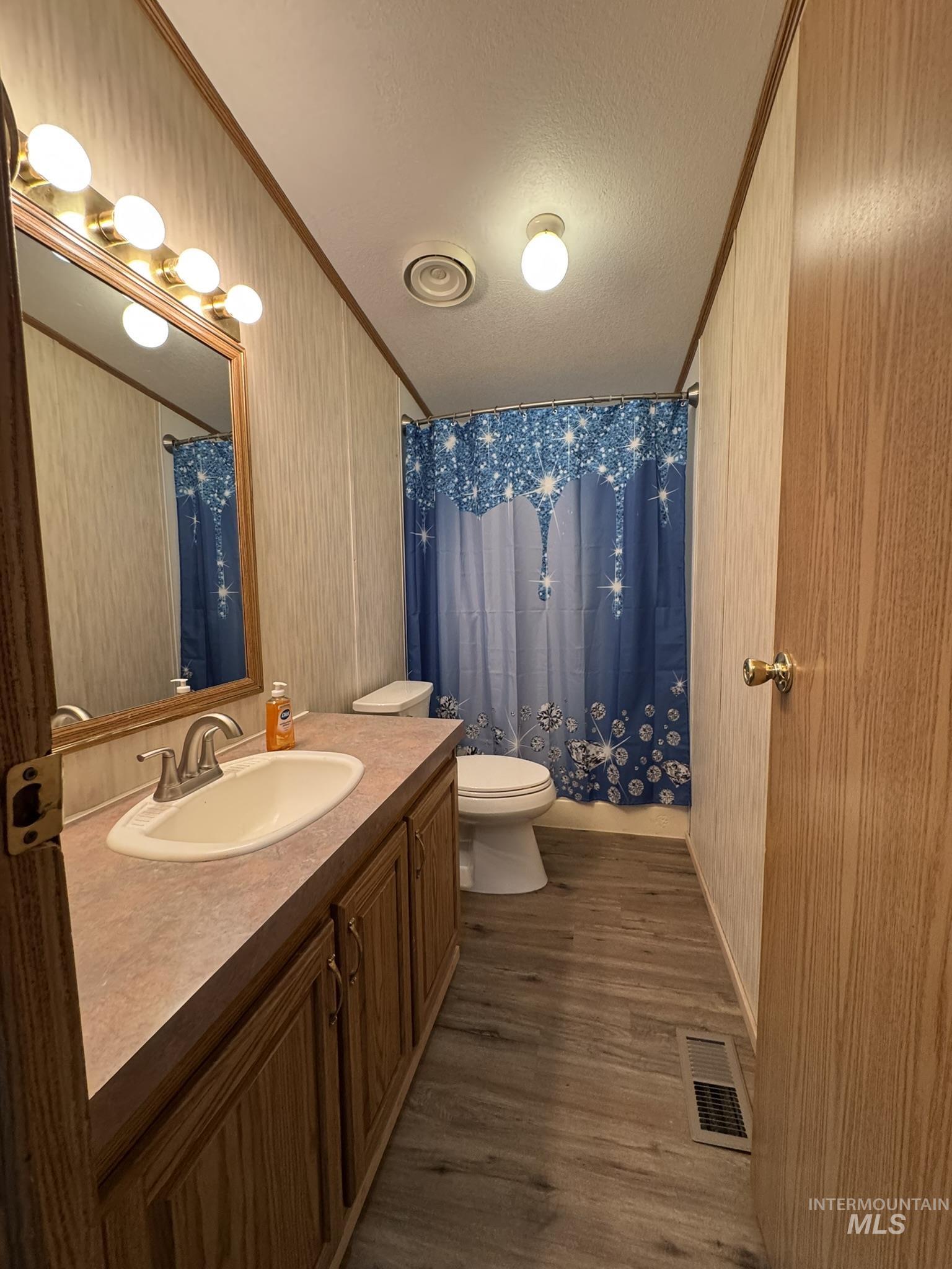 Full bathroom featuring crown molding, dark wood finished floors, vanity, and a textured ceiling