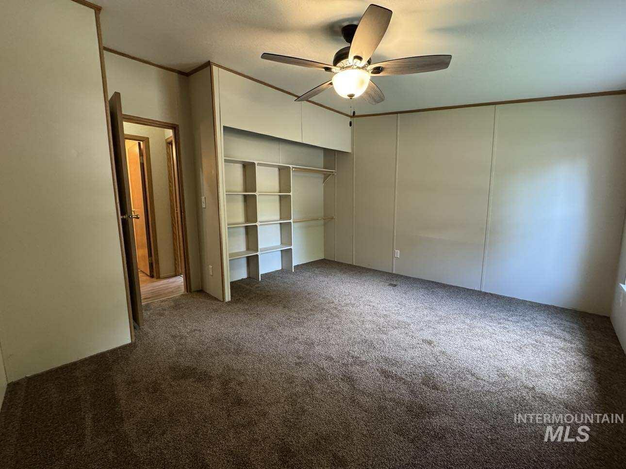 Unfurnished bedroom with crown molding, carpet floors, a closet, and a ceiling fan