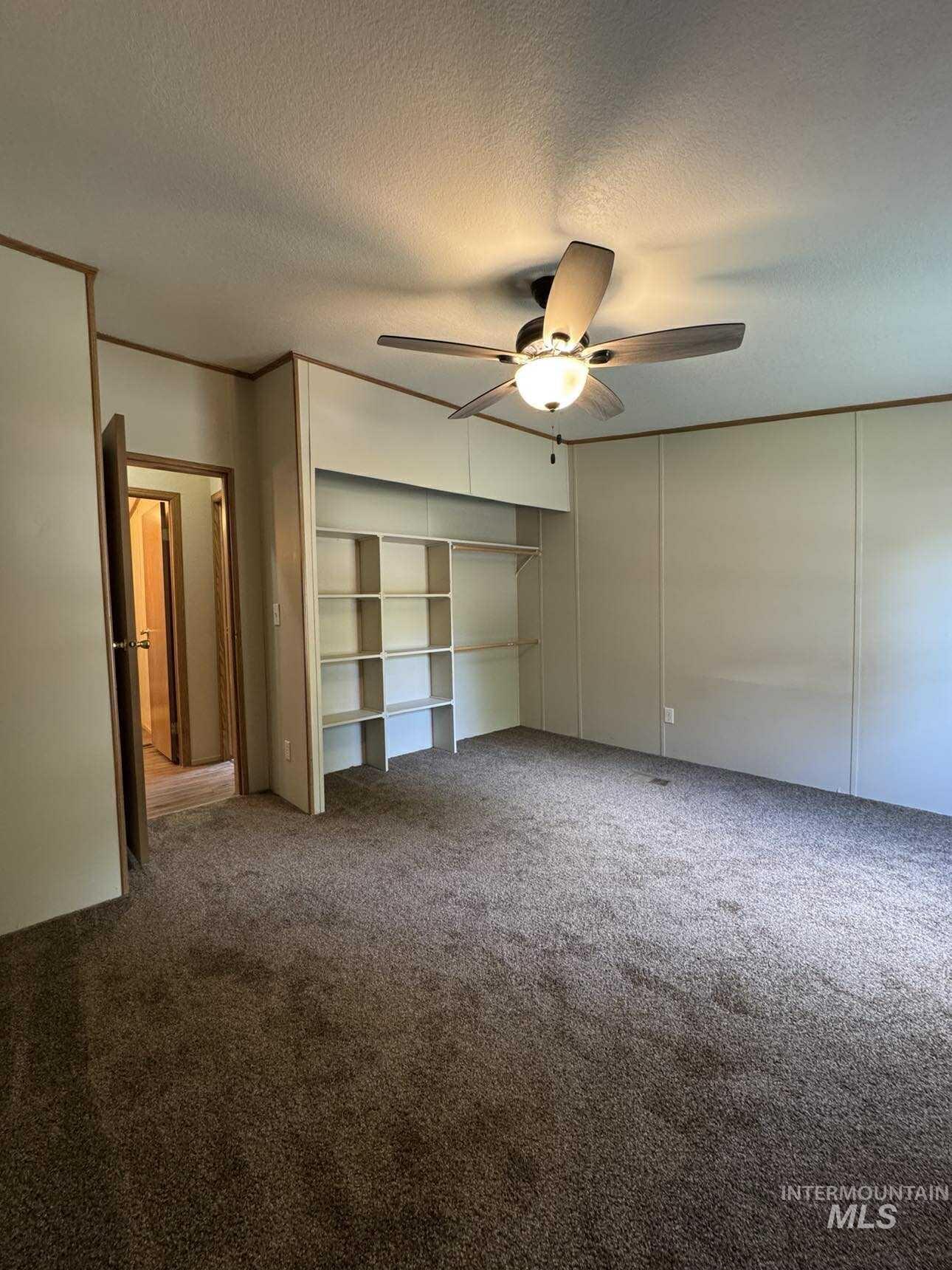 Unfurnished bedroom featuring carpet flooring, a textured ceiling, ceiling fan, and a closet