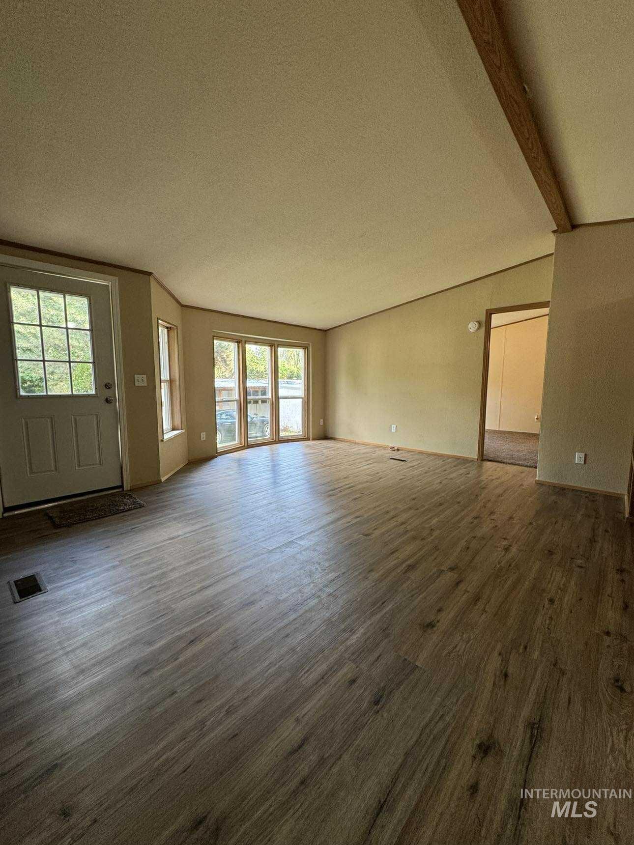 Unfurnished living room featuring dark wood-style flooring and a textured ceiling