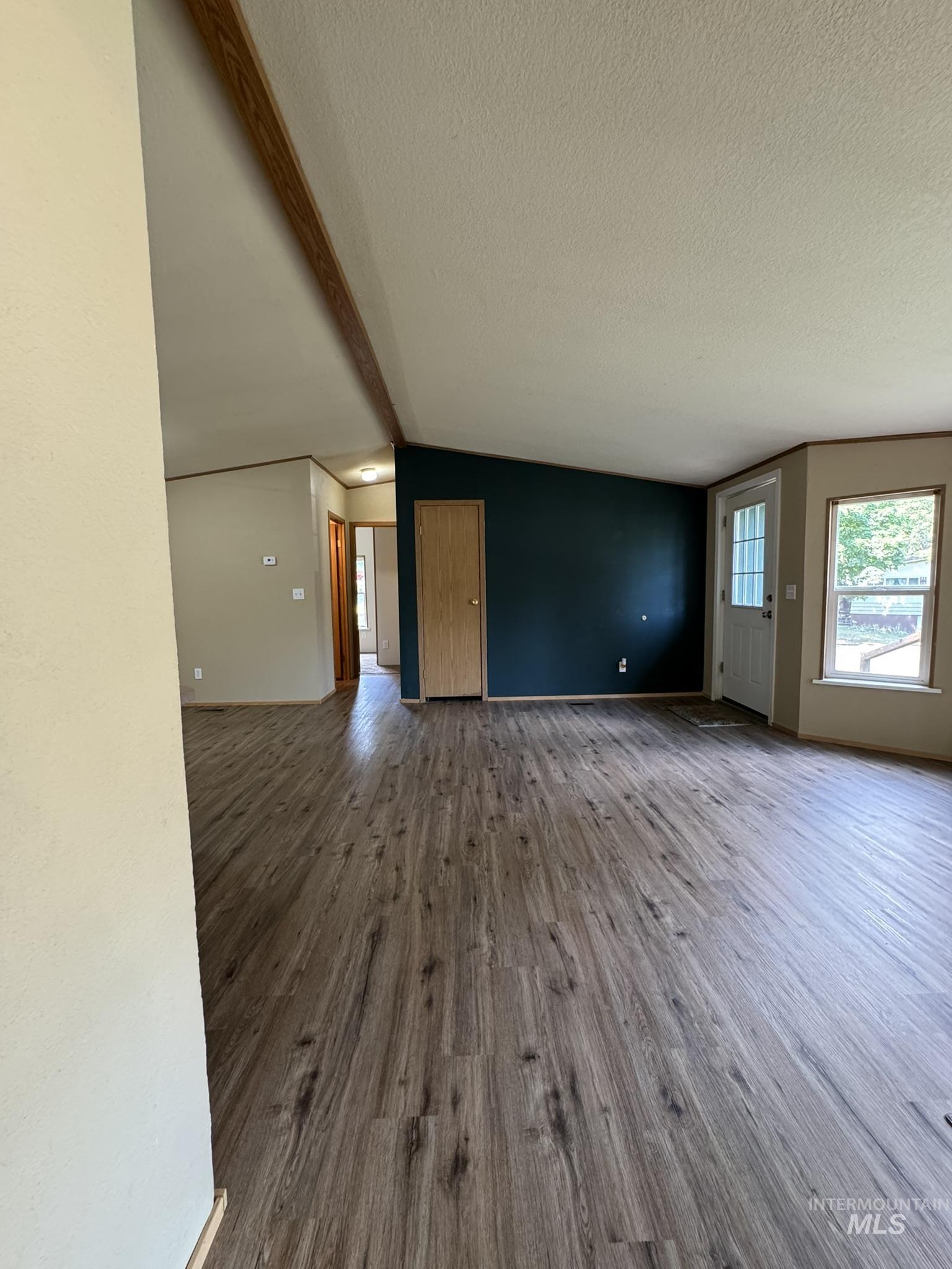 Unfurnished living room featuring dark wood finished floors, healthy amount of natural light, and a textured ceiling