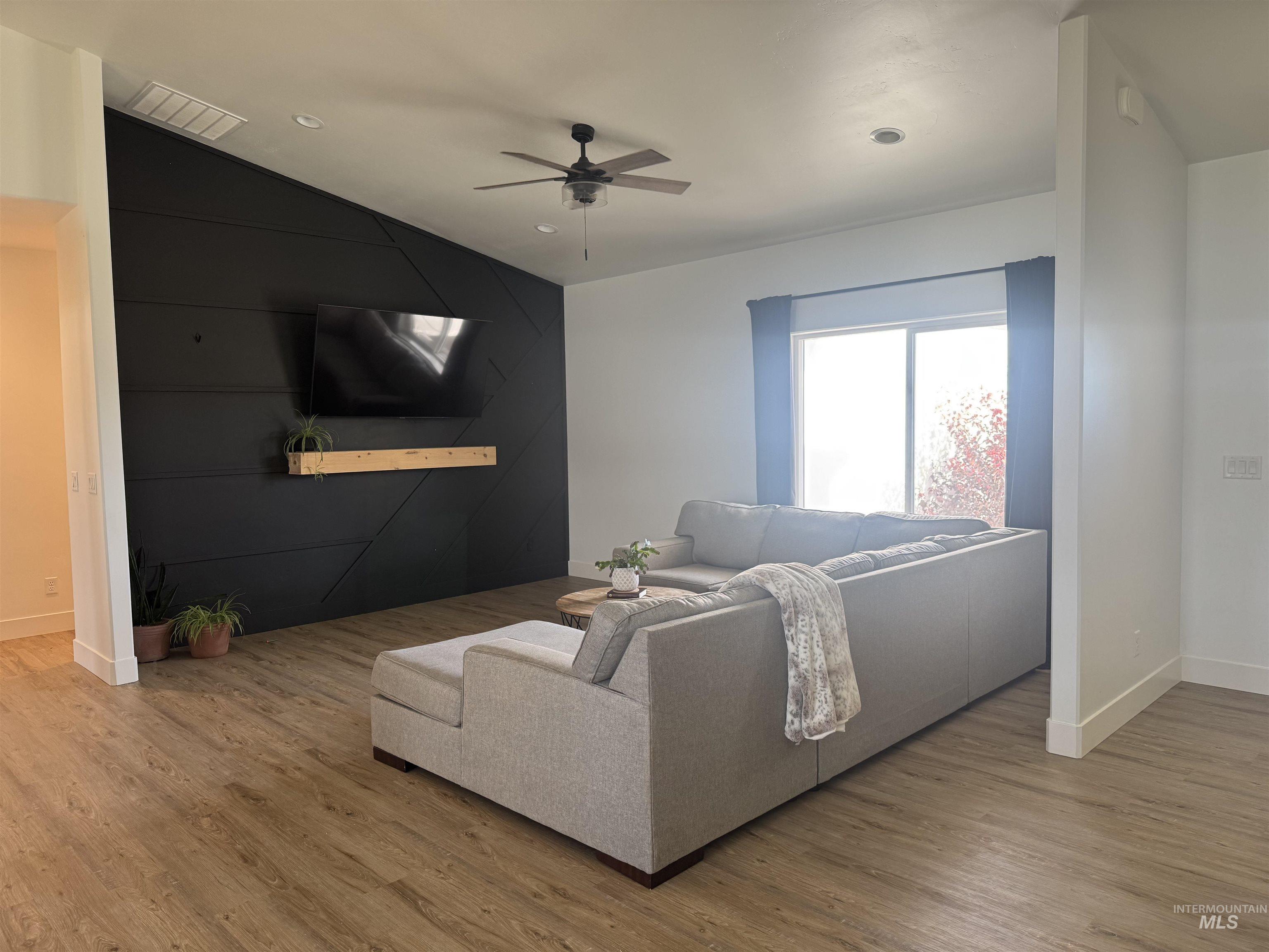 Living area featuring wood finished floors, a ceiling fan, and vaulted ceiling