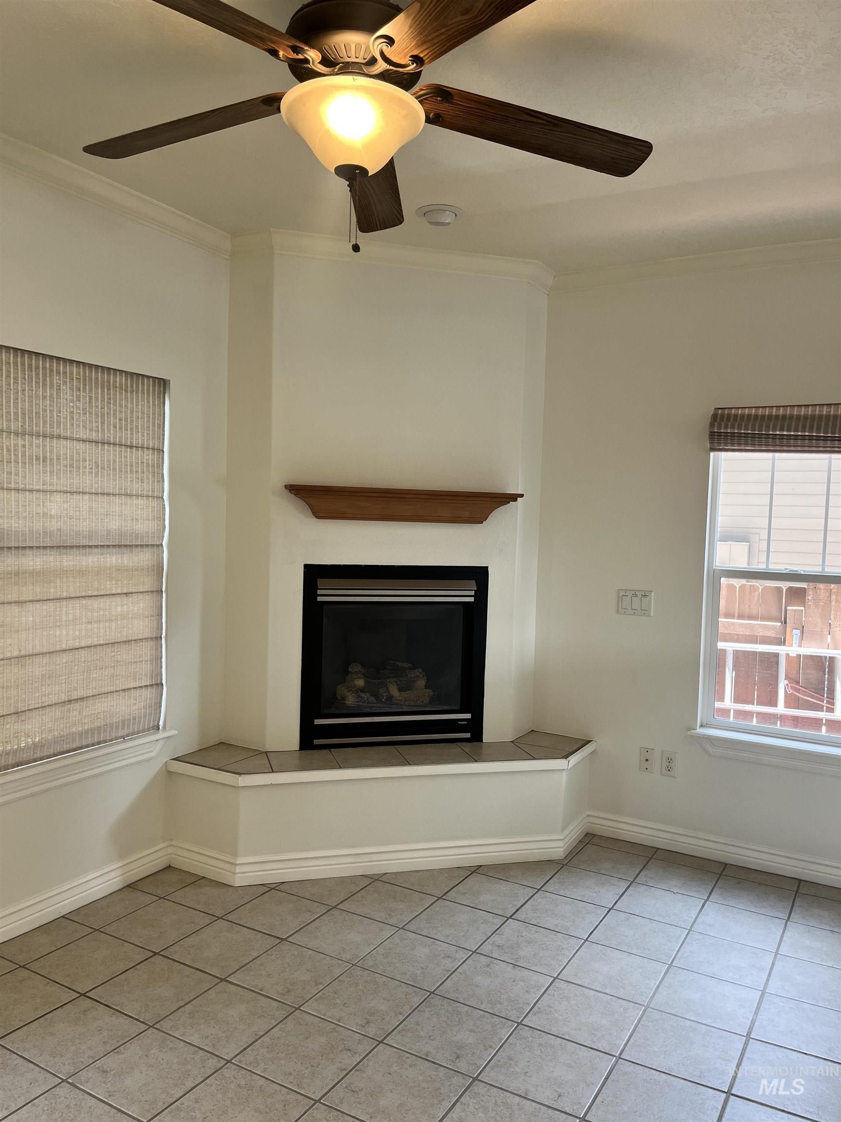 Corner fireplace with mantle, seating area, and flanked by windows on either side.