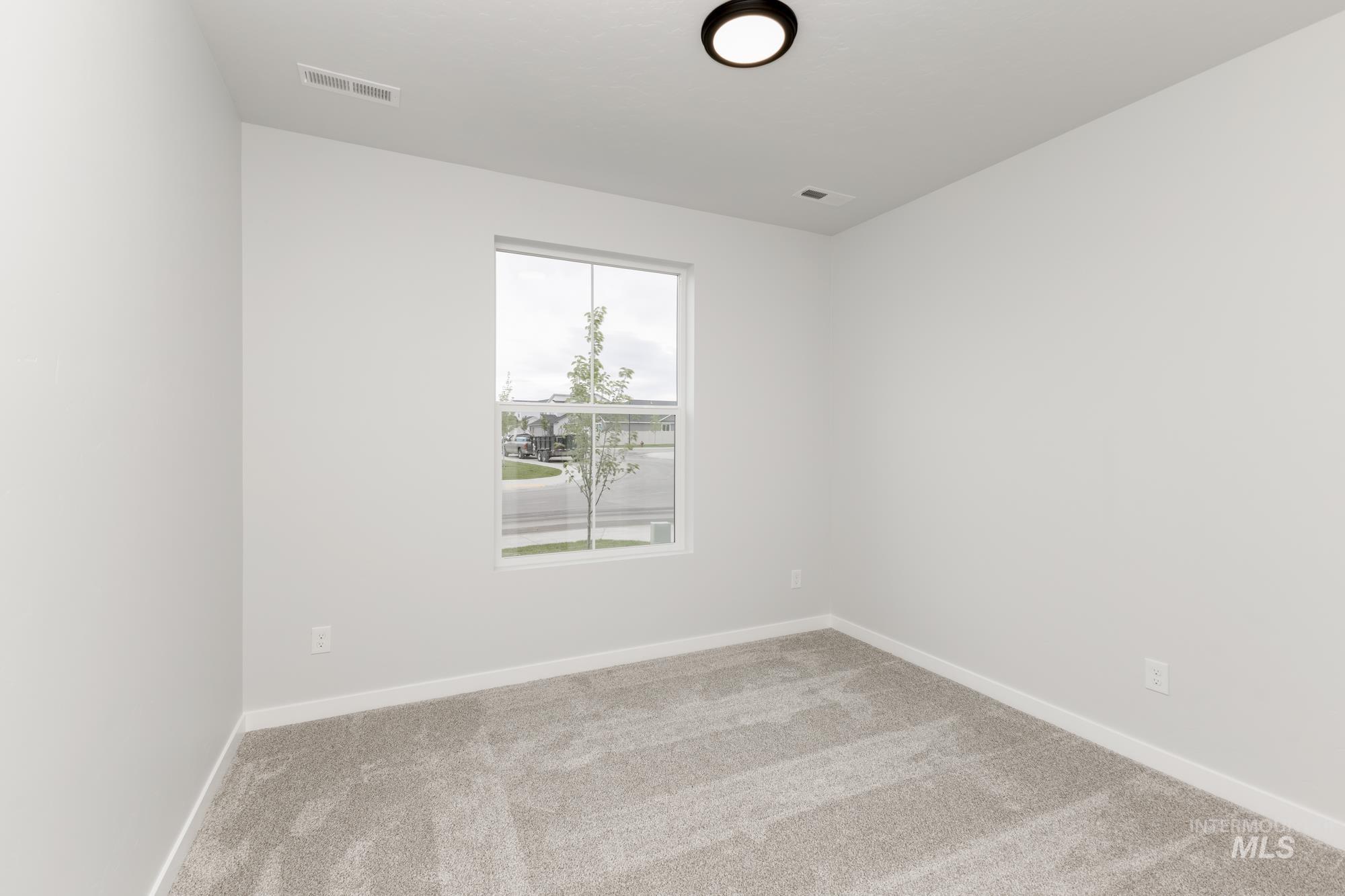 Spare room featuring carpet flooring and baseboards