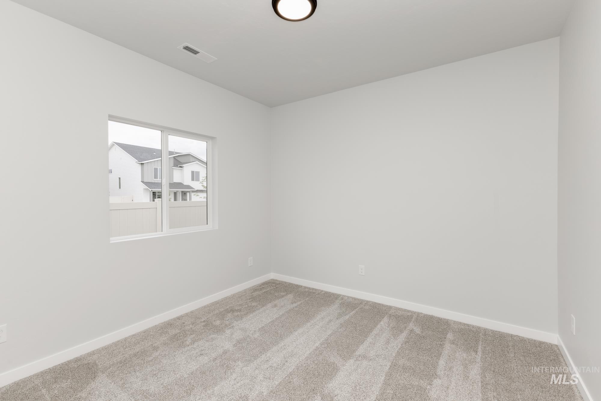 Carpeted spare room featuring baseboards