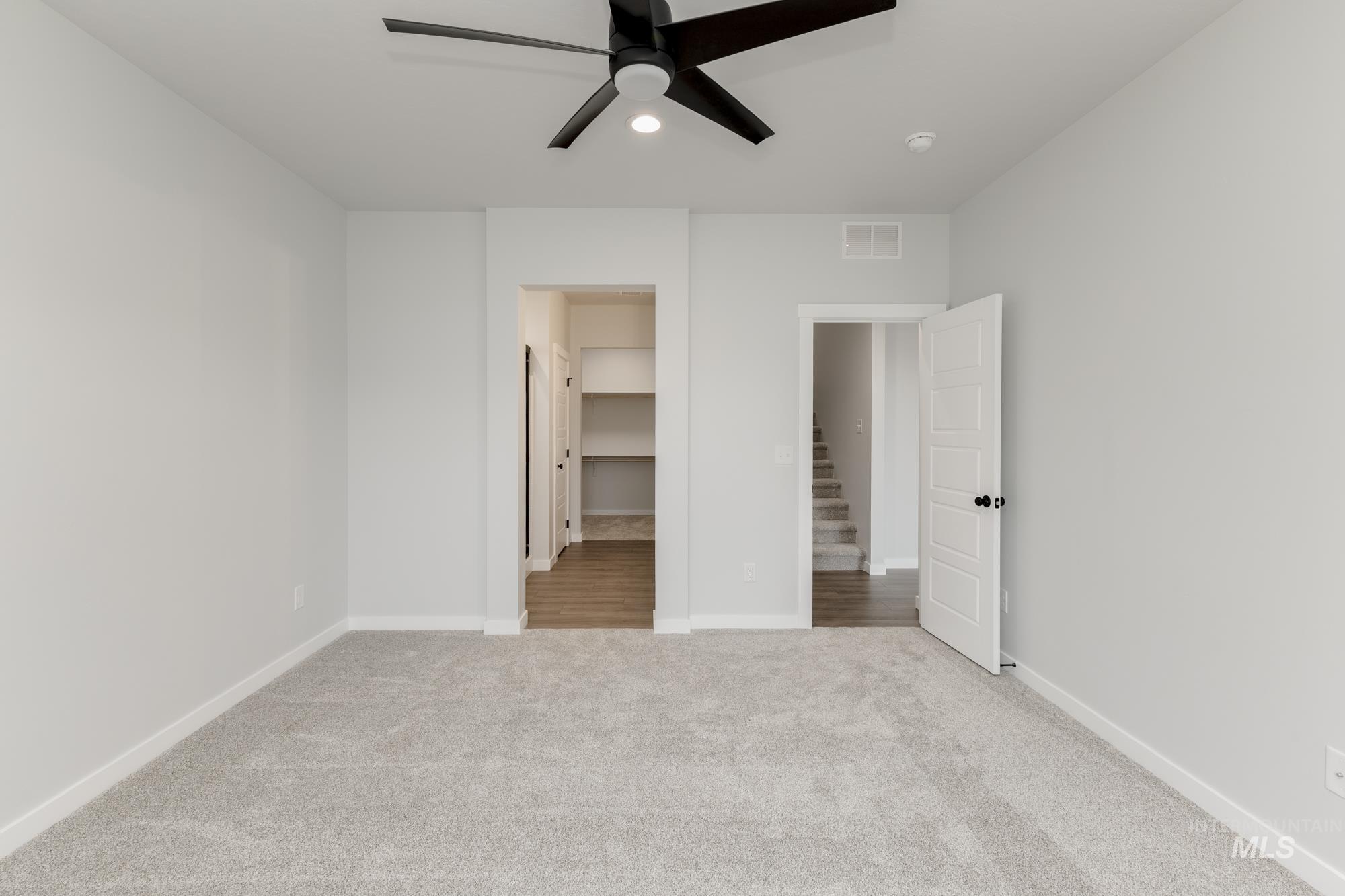 Unfurnished bedroom featuring carpet floors, a walk in closet, and ceiling fan
