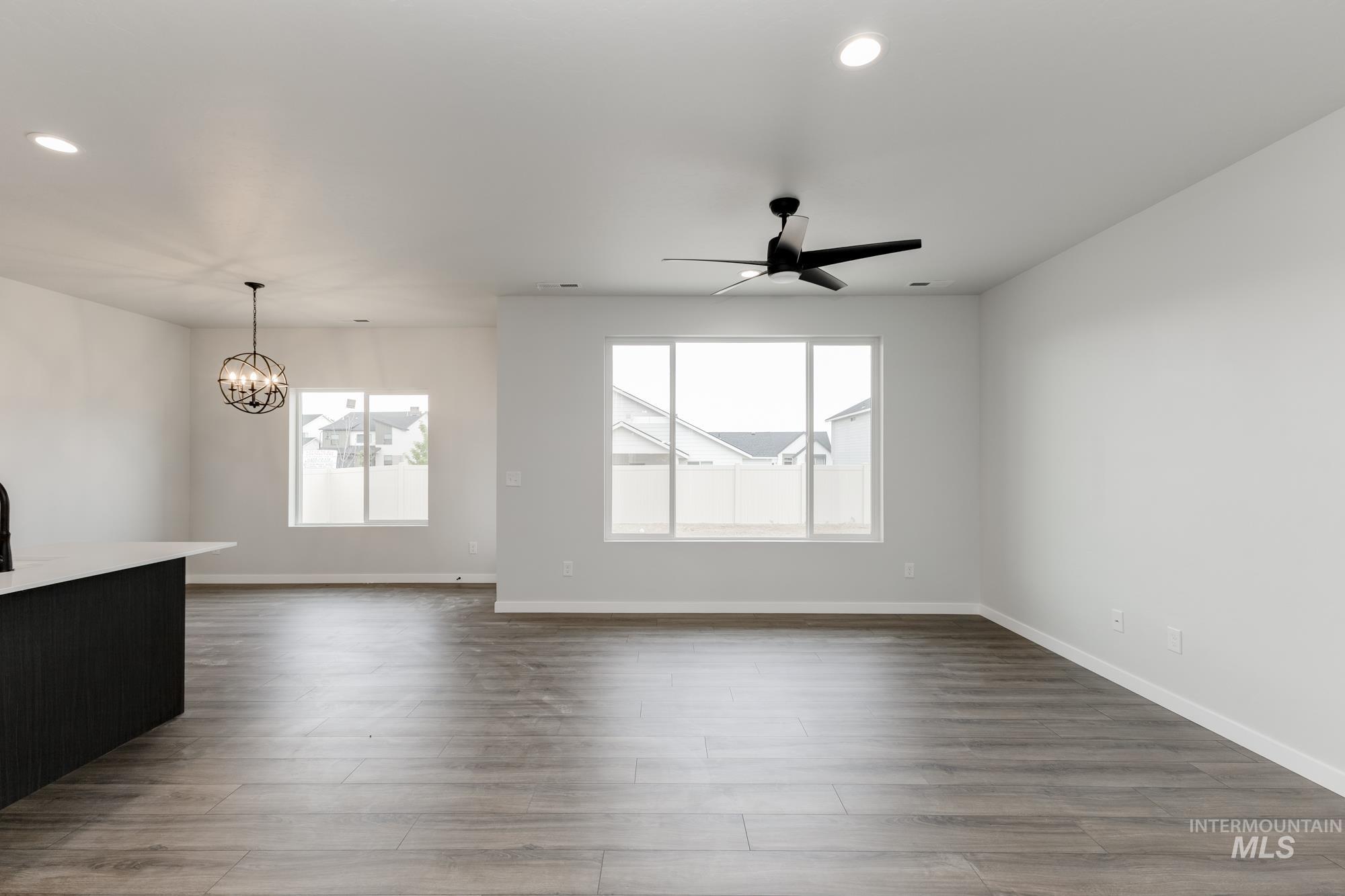 Unfurnished living room with recessed lighting, a chandelier, dark wood finished floors, and ceiling fan