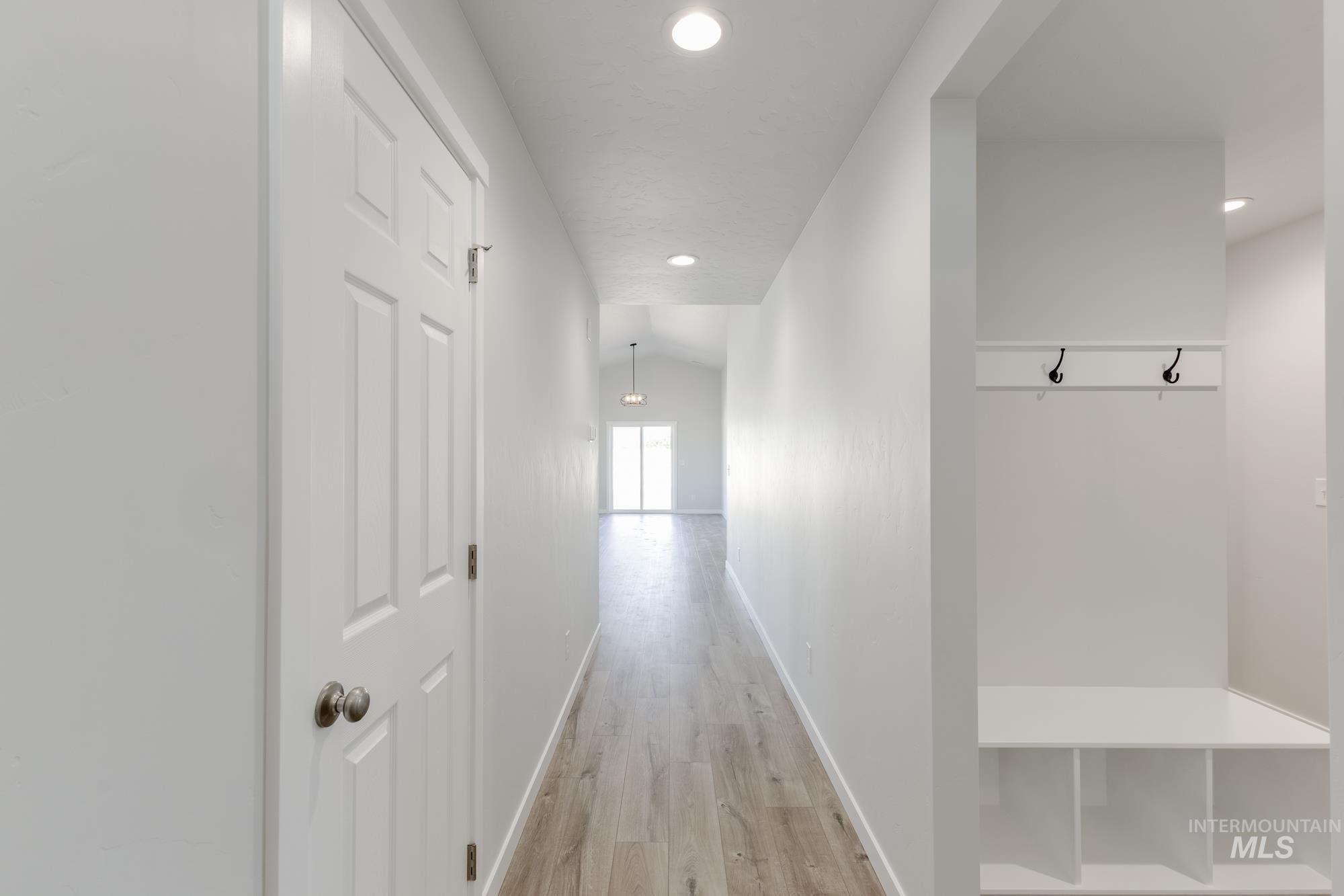 Hallway with light wood-style floors, recessed lighting, and lofted ceiling