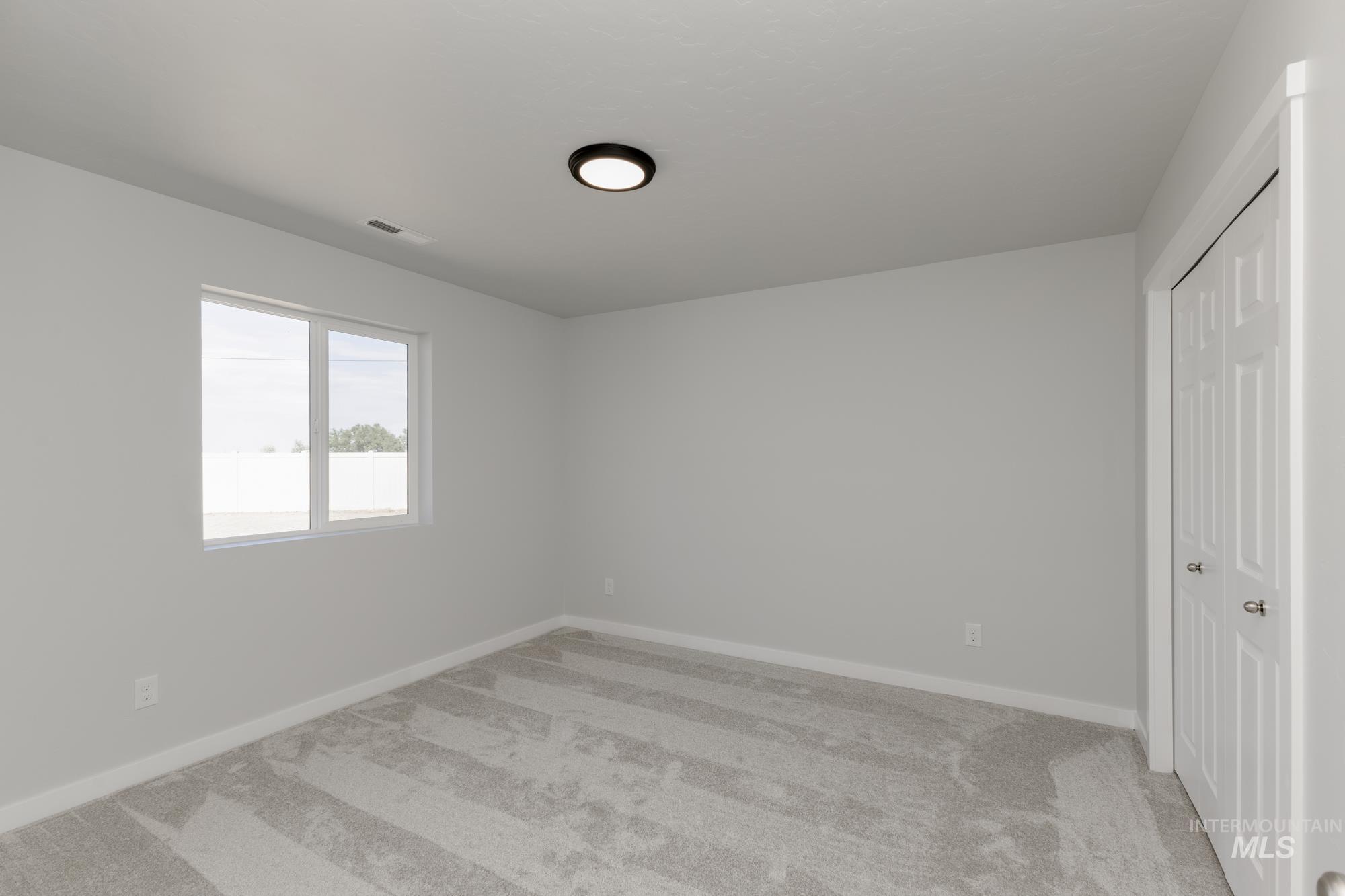 Unfurnished bedroom with light colored carpet and a closet