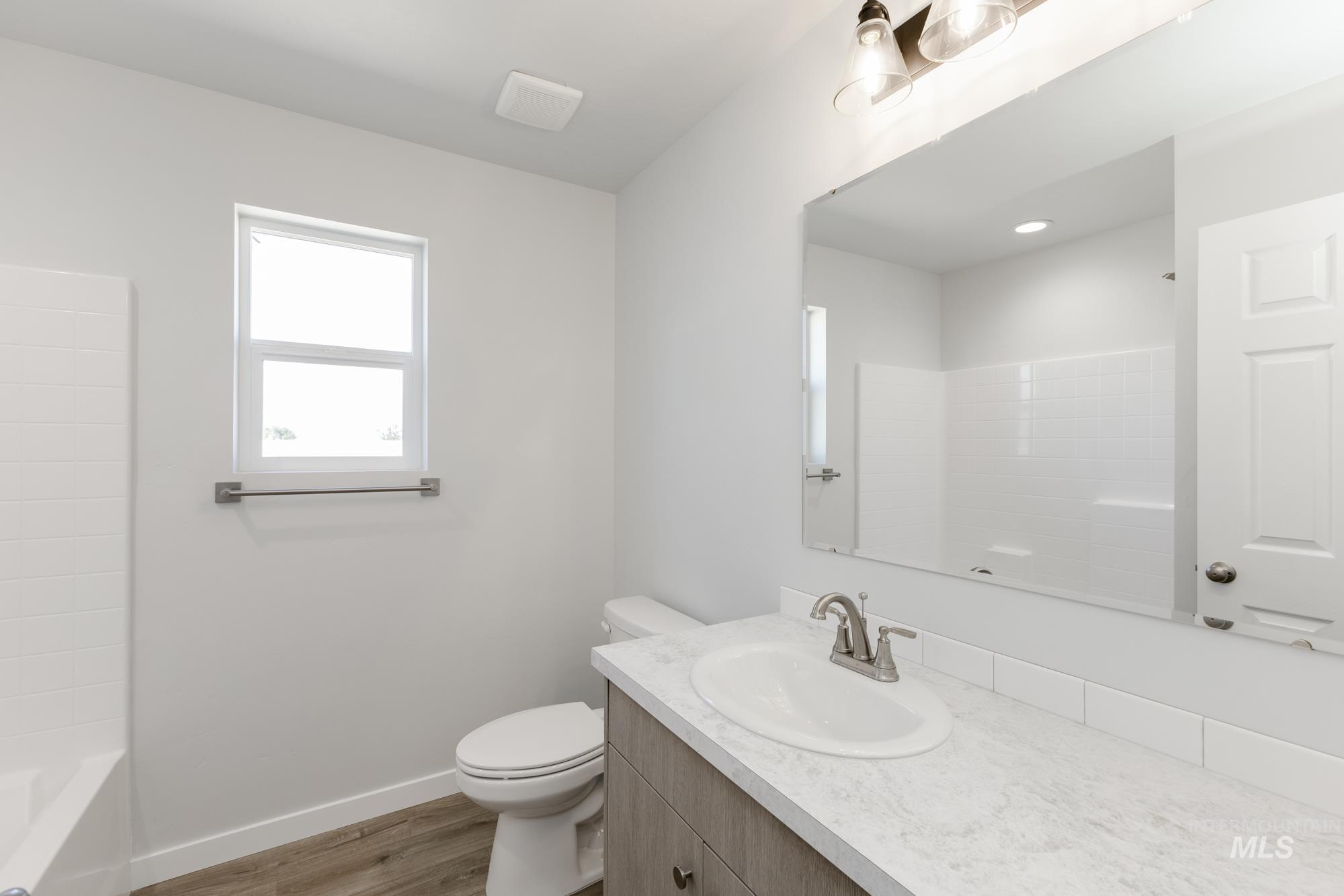 Full bathroom with light wood-style floors, vanity, and washtub / shower combination