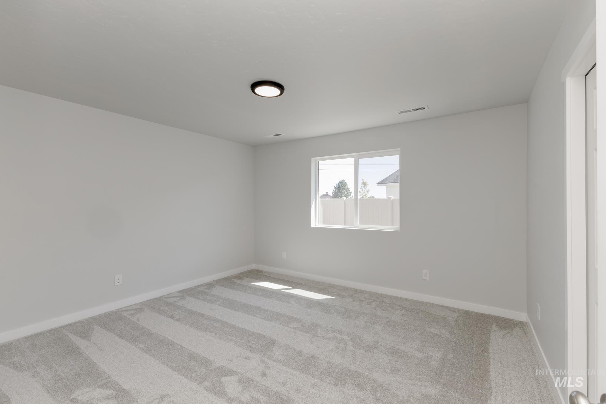 Carpeted spare room featuring baseboards