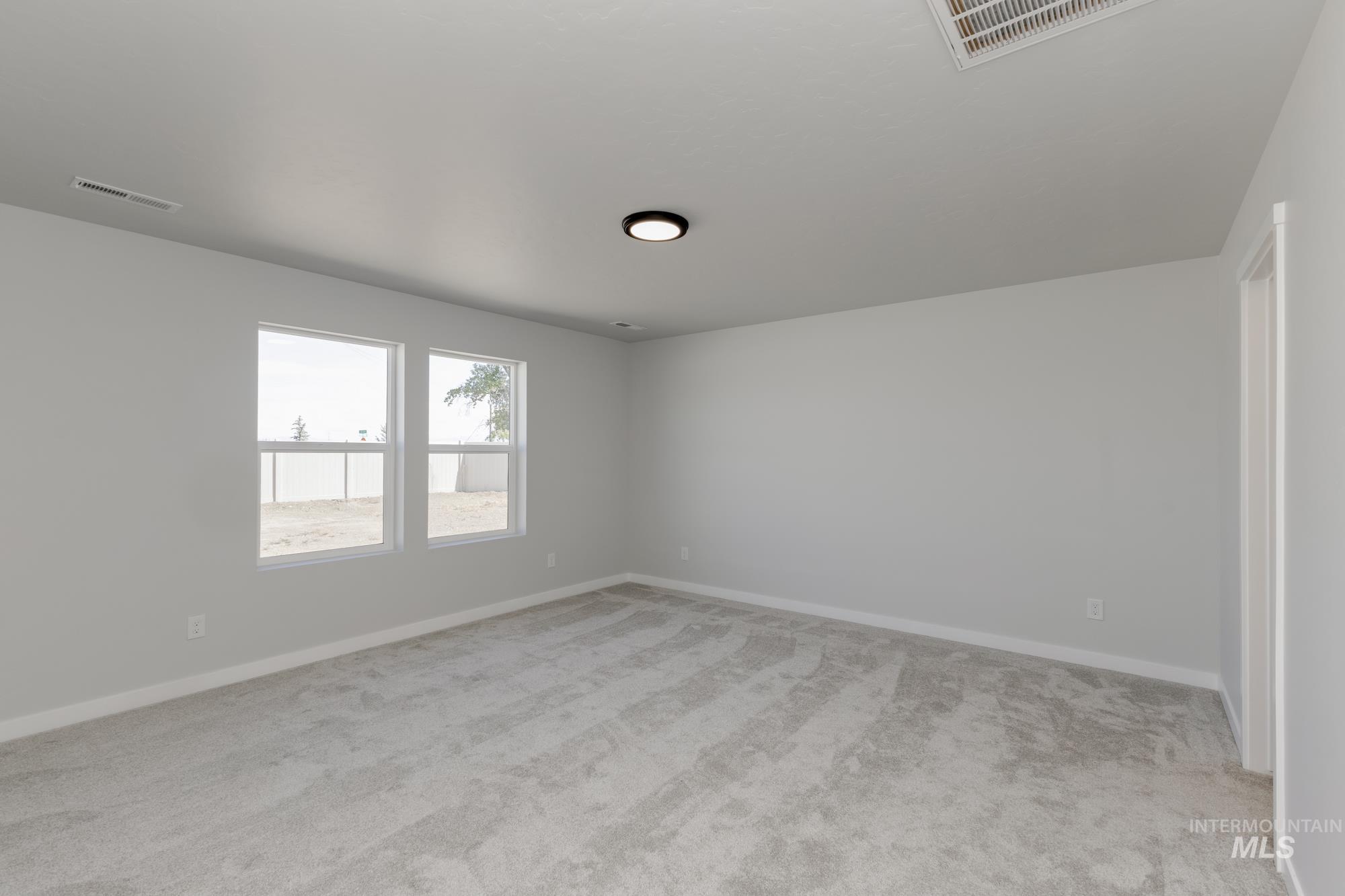 Unfurnished room featuring light carpet and baseboards