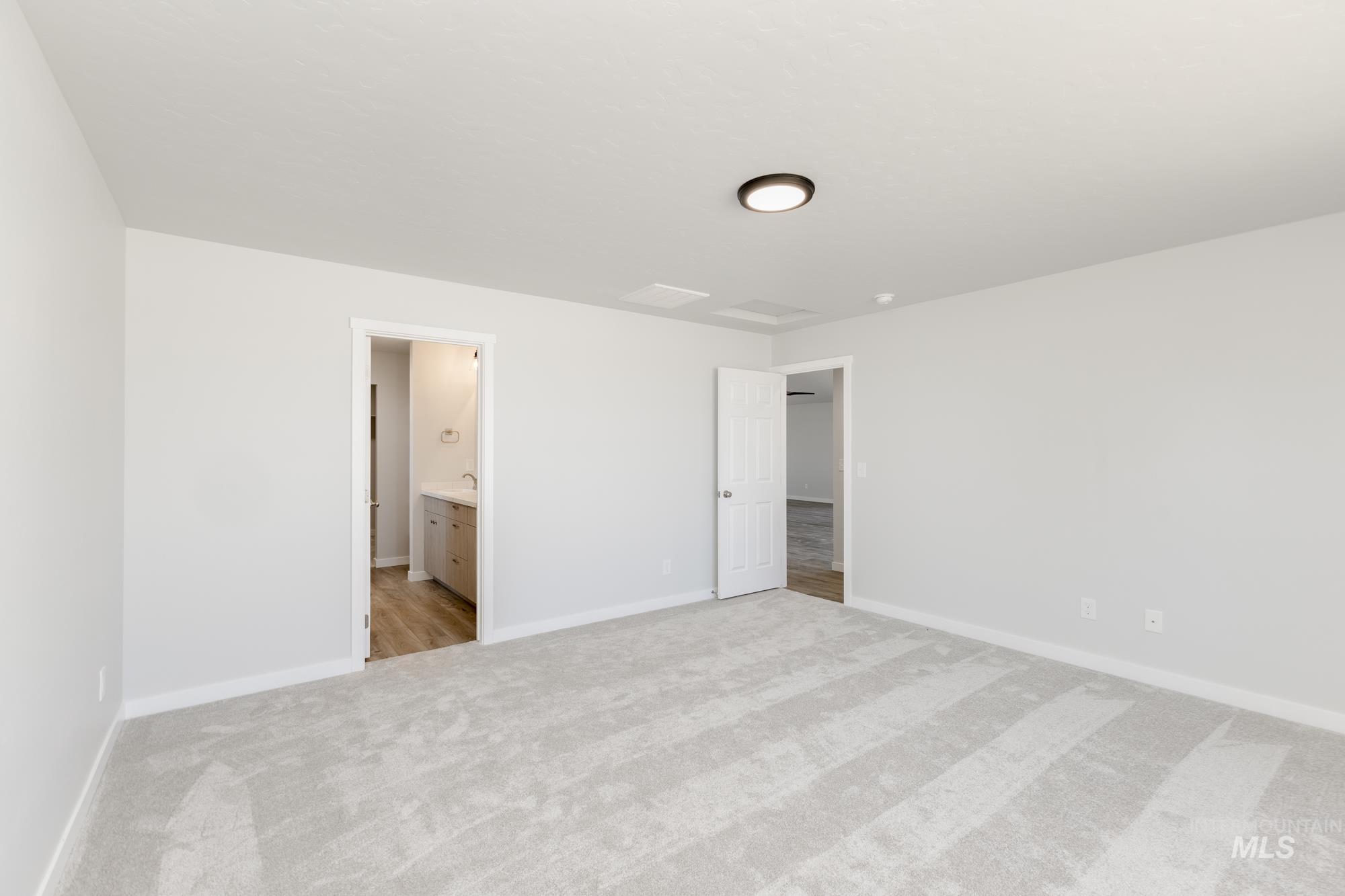 Unfurnished bedroom featuring light carpet and ensuite bath