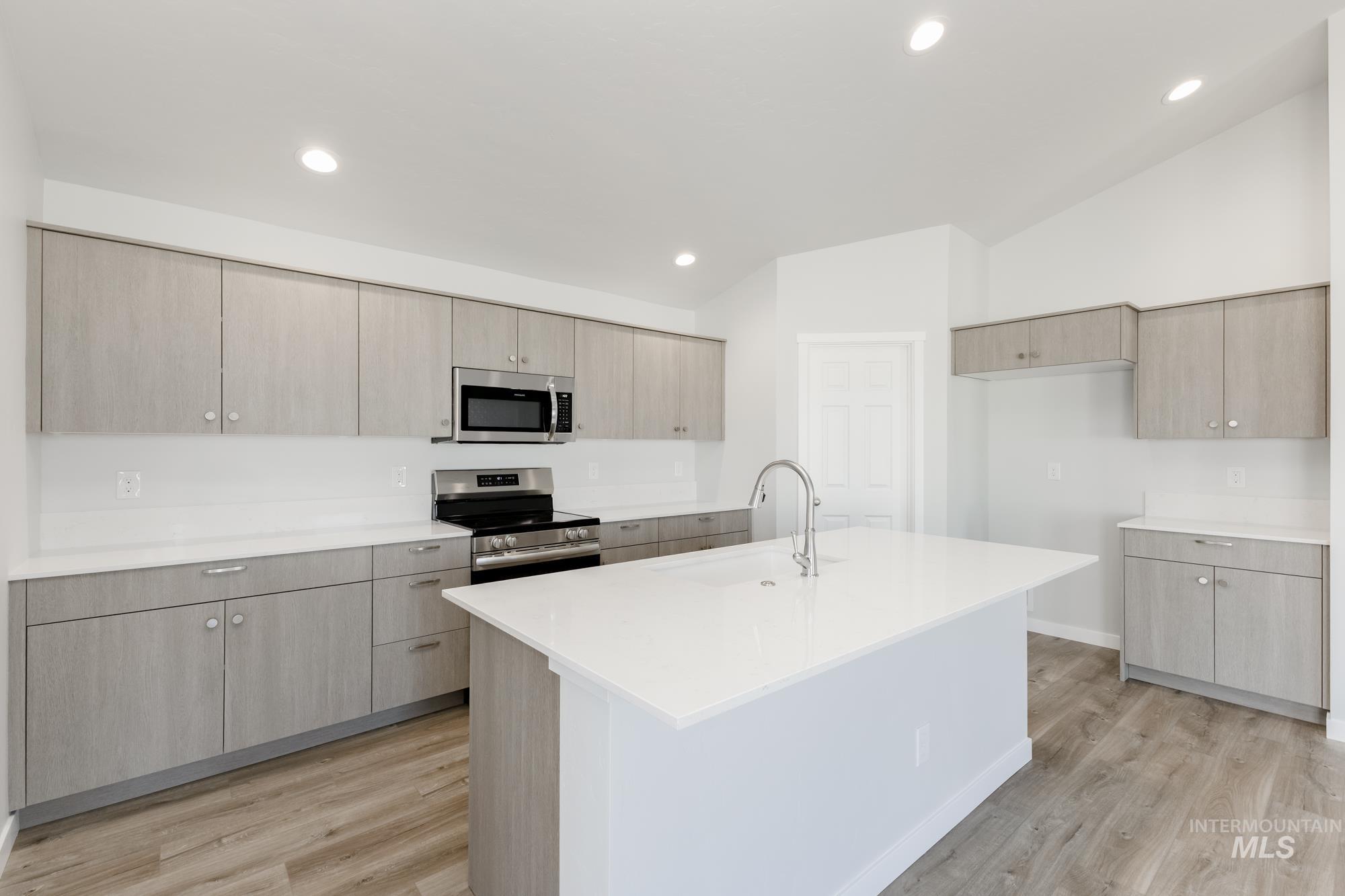 Kitchen with stainless steel appliances, modern cabinets, light wood-style flooring, light brown cabinets, and recessed lighting